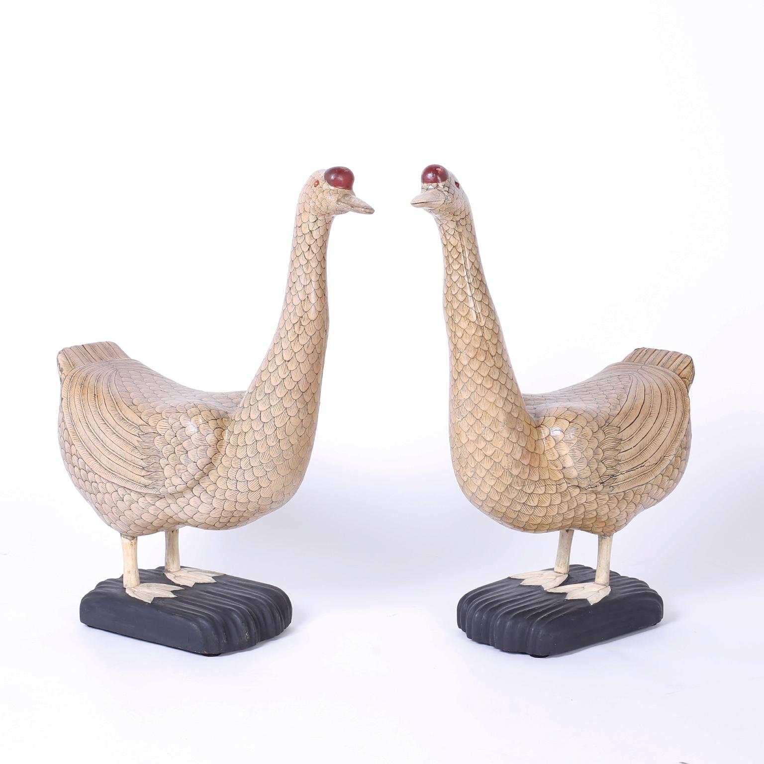 Perky pair of Chinese geese with amusing expressions crafted in carved wood and painted with stylized feathers. Featuring carved bone beaks and feet.