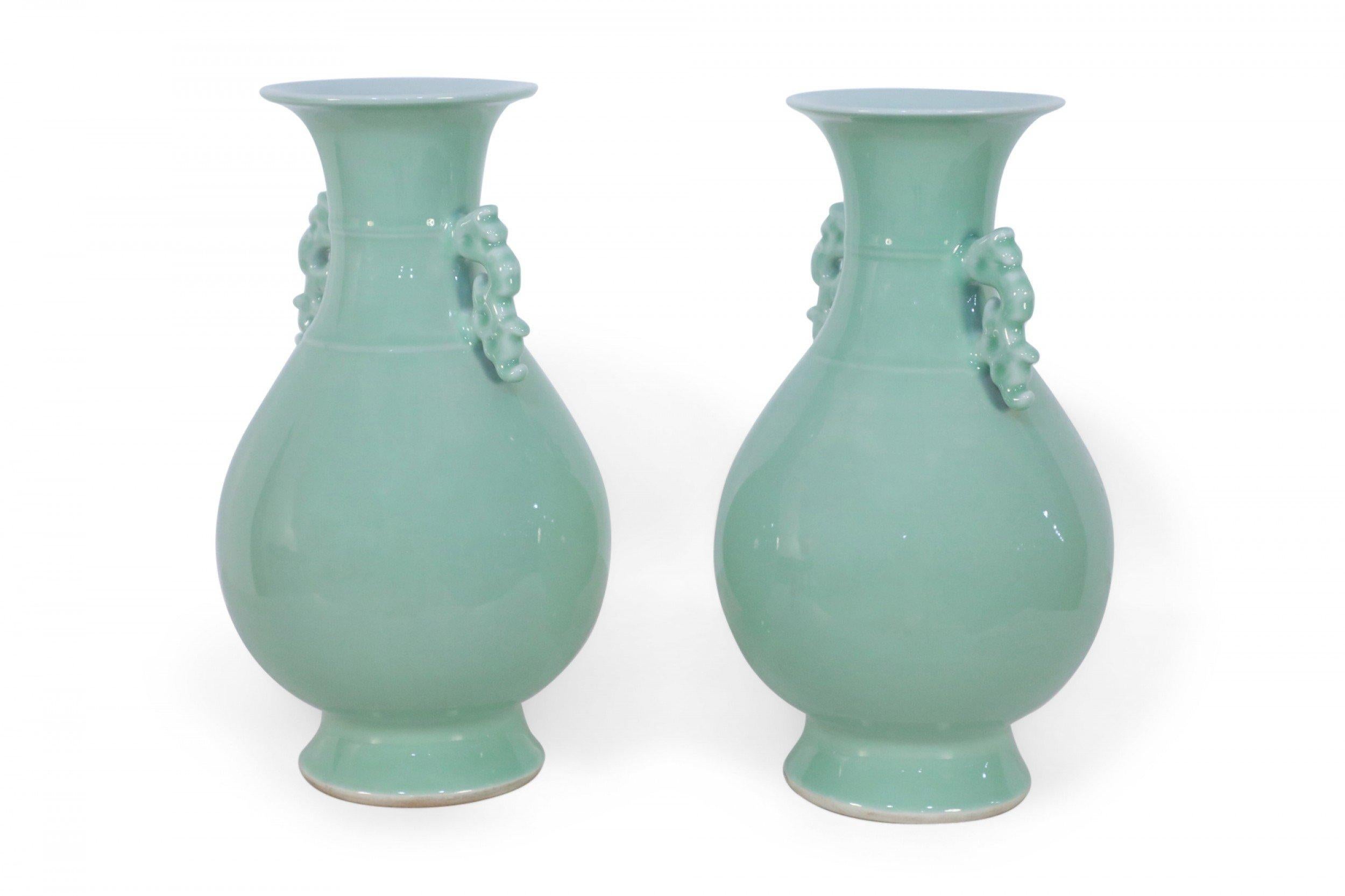 Pair of Chinese celadon colored vases with baluster shapes, accented at the necks with scrolled ears, each sitting atop a round foot (priced as pair).
   