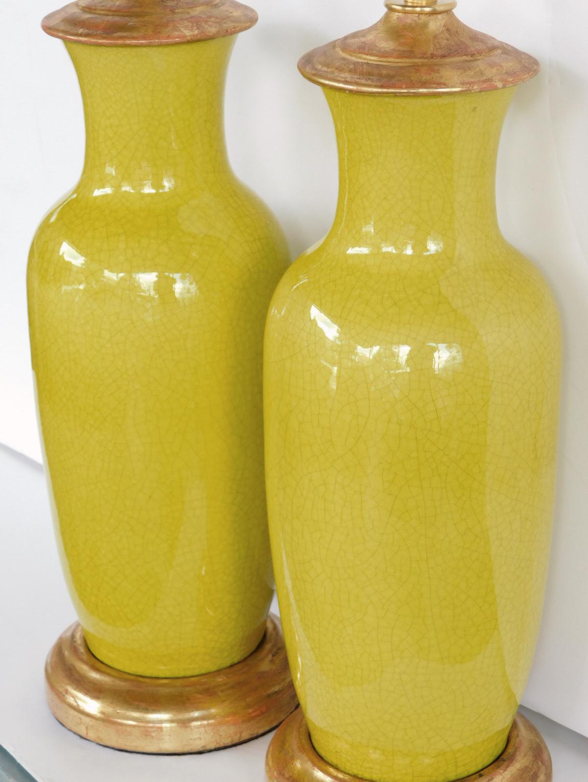 Each with flaring neck above a tapering body all in a vibrant chartreuse-yellow crackle glaze; resting on a custom giltwood base, measures: height 13