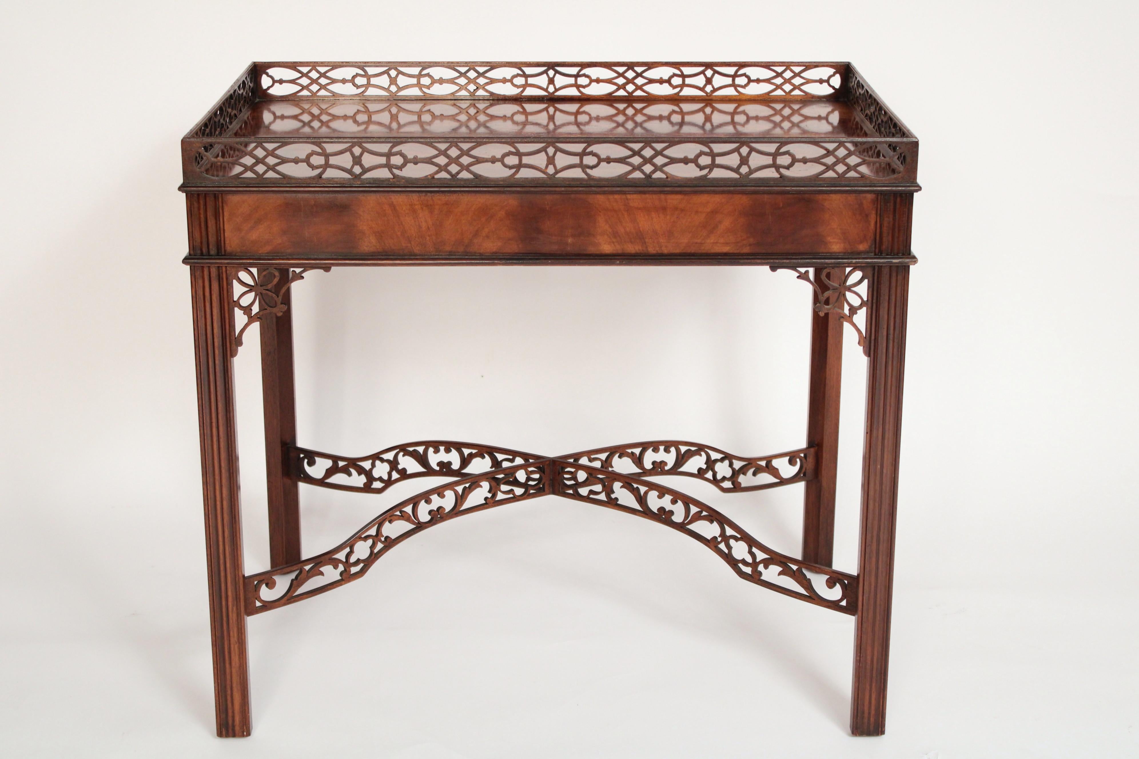 Pair of Chinese  Chippendale style mahogany end tables made by Baker Furniture Company, circa 1980's. With reticulated mahogany gallery's surrounding flame mahogany tops, the frieze with candle pull outs on each end, reticulated mahogany corner