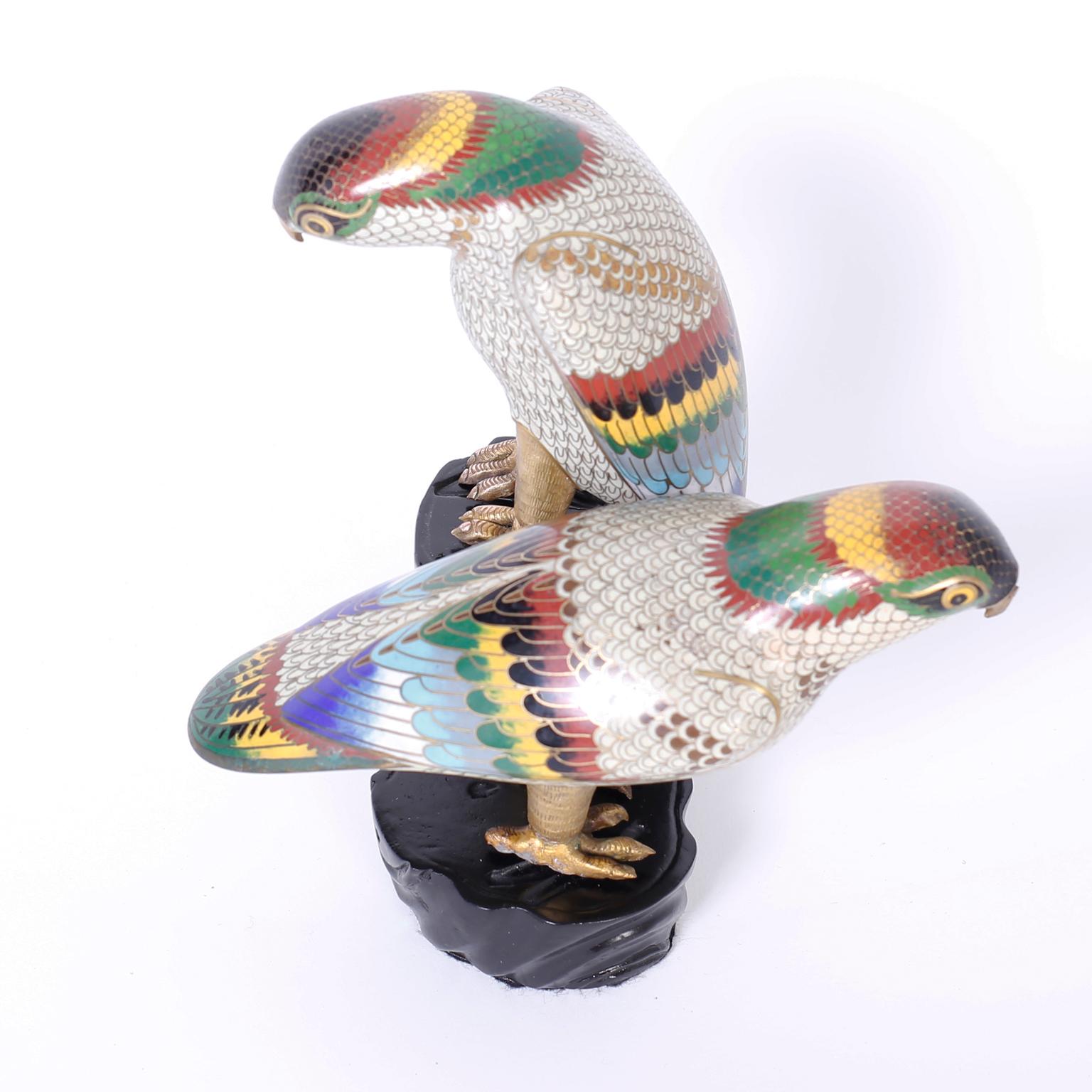 Refined pair of Chinese cloisonné parrots with colorful plumage, quizzical expressions and uniquely perched on a carved wood faux tree trunk.