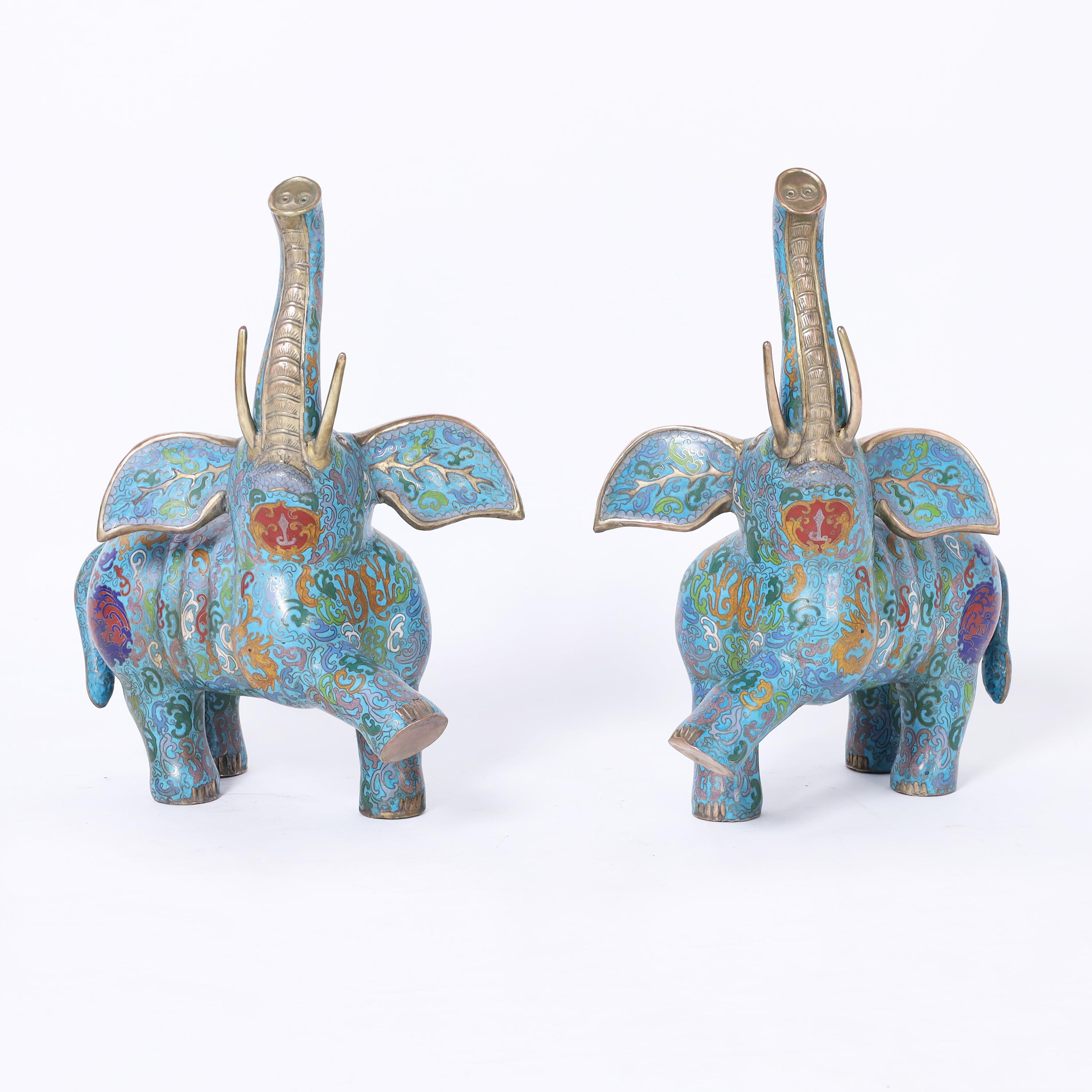 Enchanting pair of vintage Chinese cloisonne or enamel on brass elephants in a dancing pose having floral symbolic designs on an alluring blue background. Trunk up for good luck. 