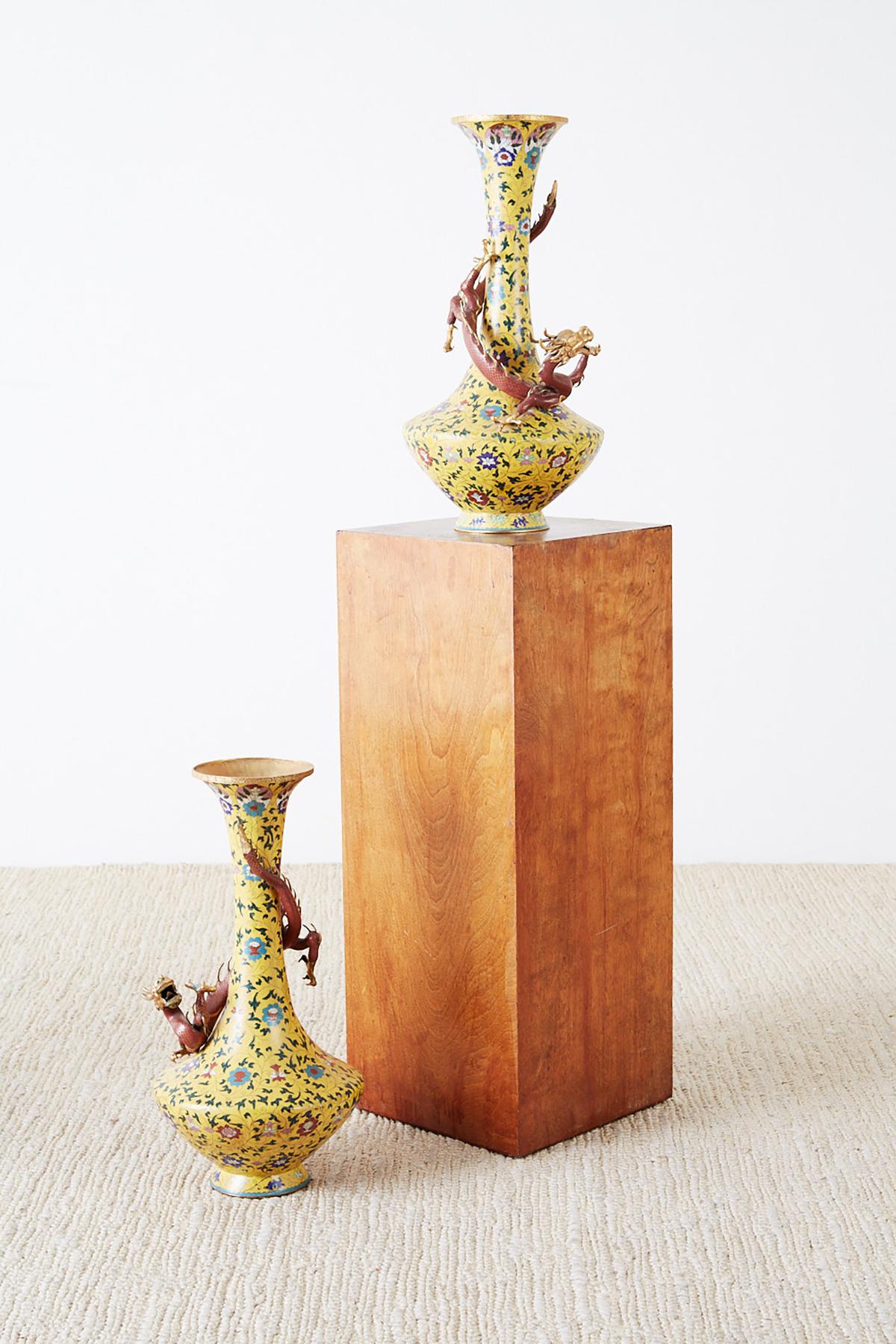 Fantastic pair of early 20th century cloisonné vases featuring mounted Chilong dragons encircling the necks. Colorful imperial yellow ground decorated with intricate floral vine patterns and gilt accents. Beautifully formed vases each having a gilt