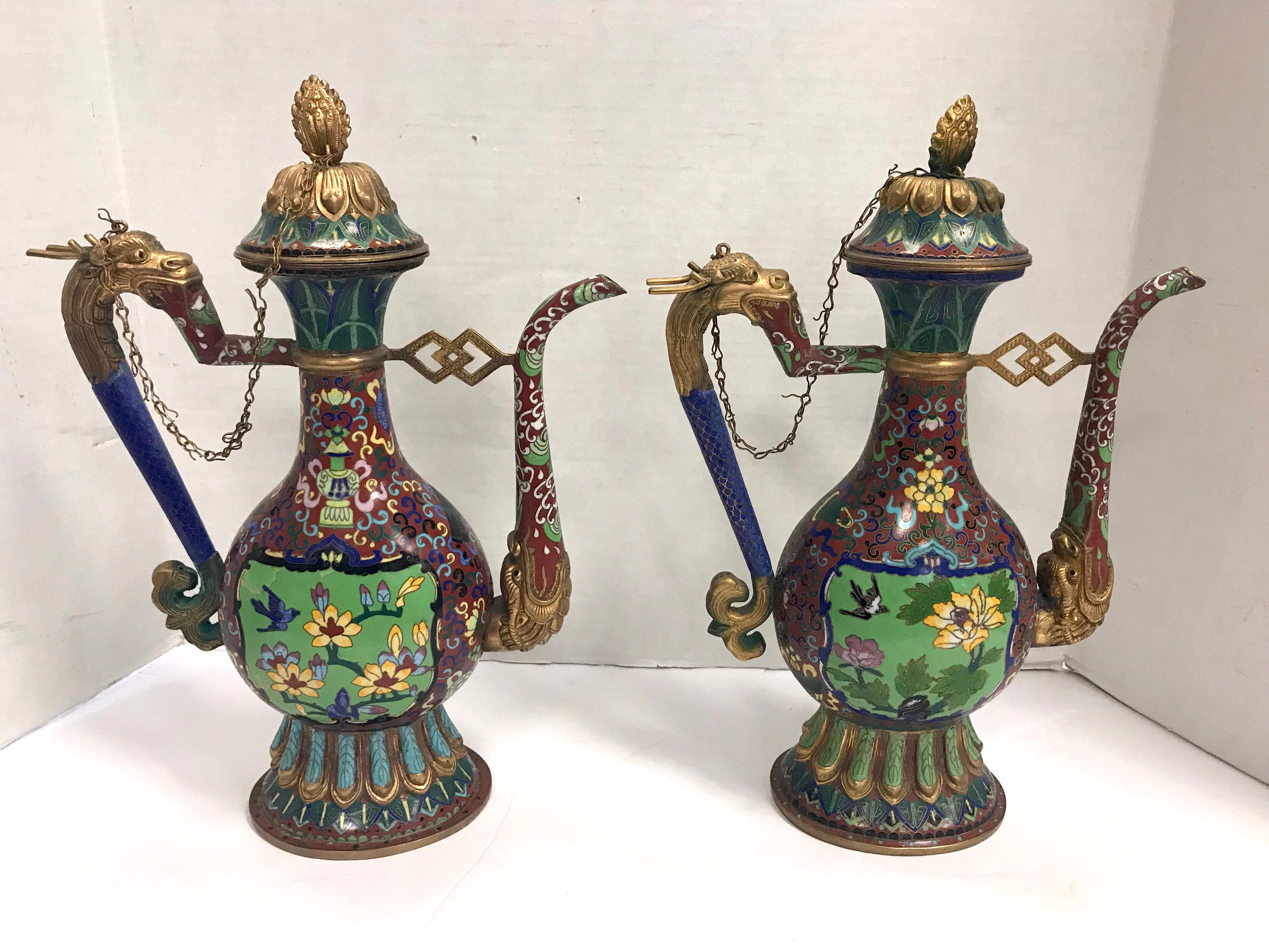 Stunning pair of coveted Chinese Cloisonne ewers or pitchers. The colors are still
vibrant and vivid. There is a chain that connects the lid to the body of each piece.
