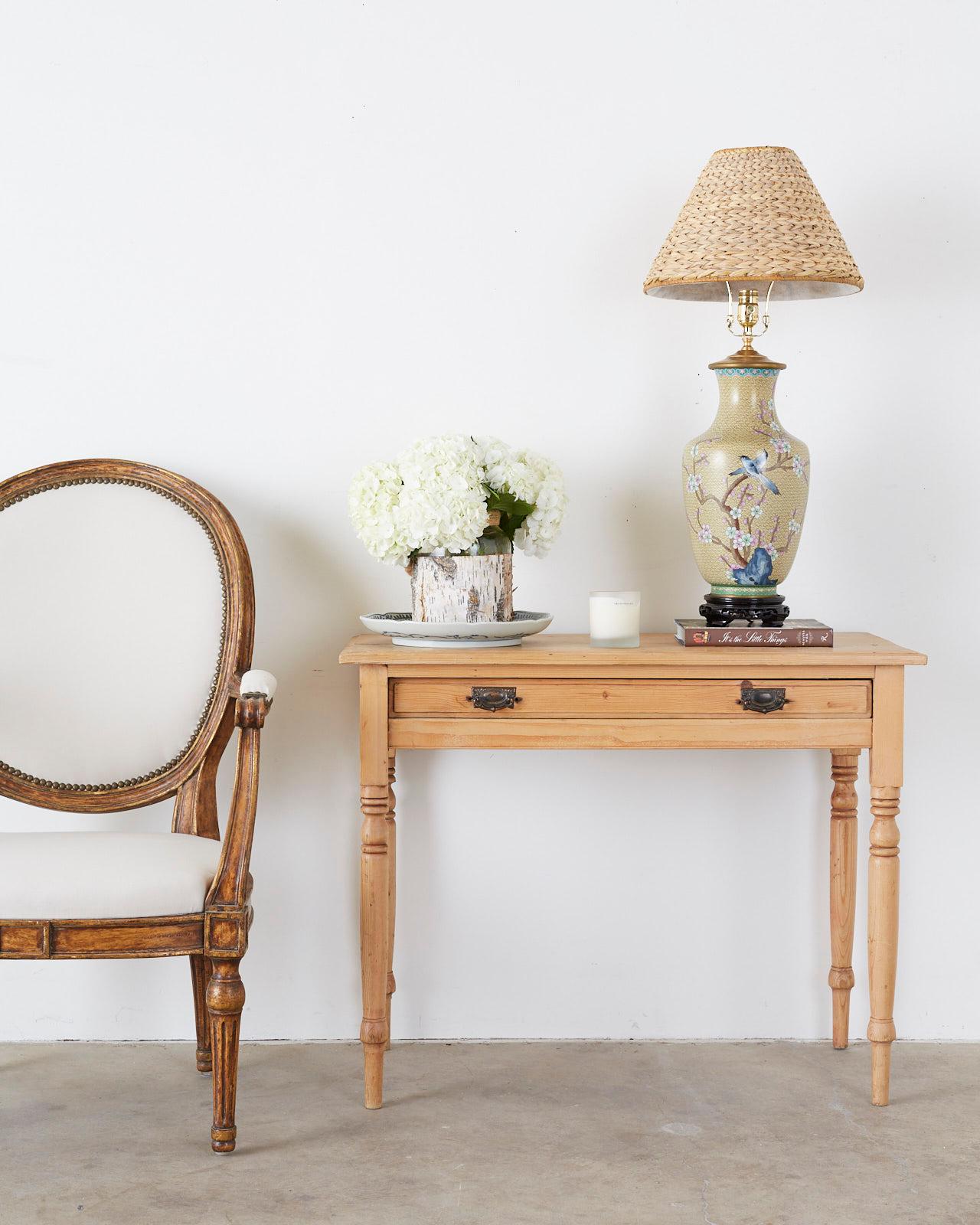 Gorgeous pair of large Chinese cloisonne vases featuring spring floral blooms, butterflies, and bluebirds. Mounted on wood stands with decorative carving and shaped feet. The vases are topped with lids surmounted by polished brass hardware, harps,