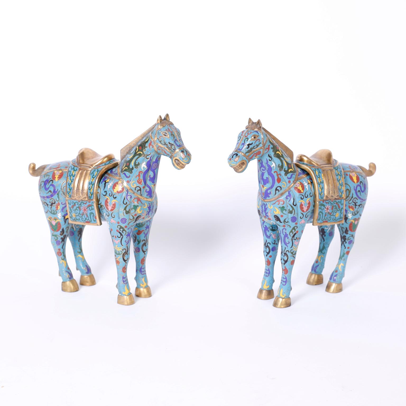 Impressive pair of Chinese cloisonné or enamel on brass horses with removable saddles and decorated from head to hoof with ancient symbolic symbols over a blue background.