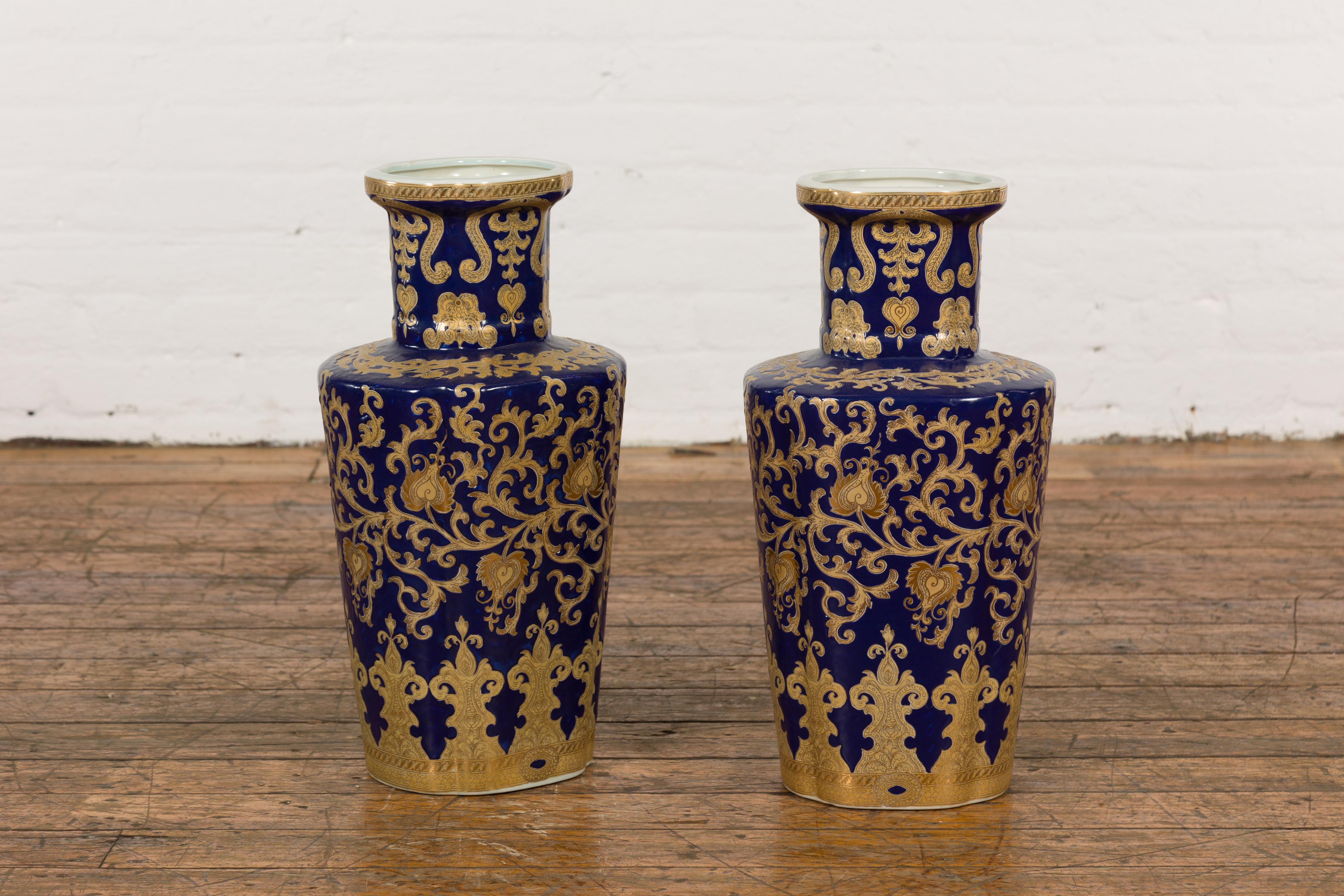A pair of vintage Chinese cobalt blue and gold porcelain altar vases with scrolling foliage and heart motifs. Delight in the exquisite artistry of this pair of vintage Chinese altar vases, presenting a captivating dance of cobalt blue and gold.