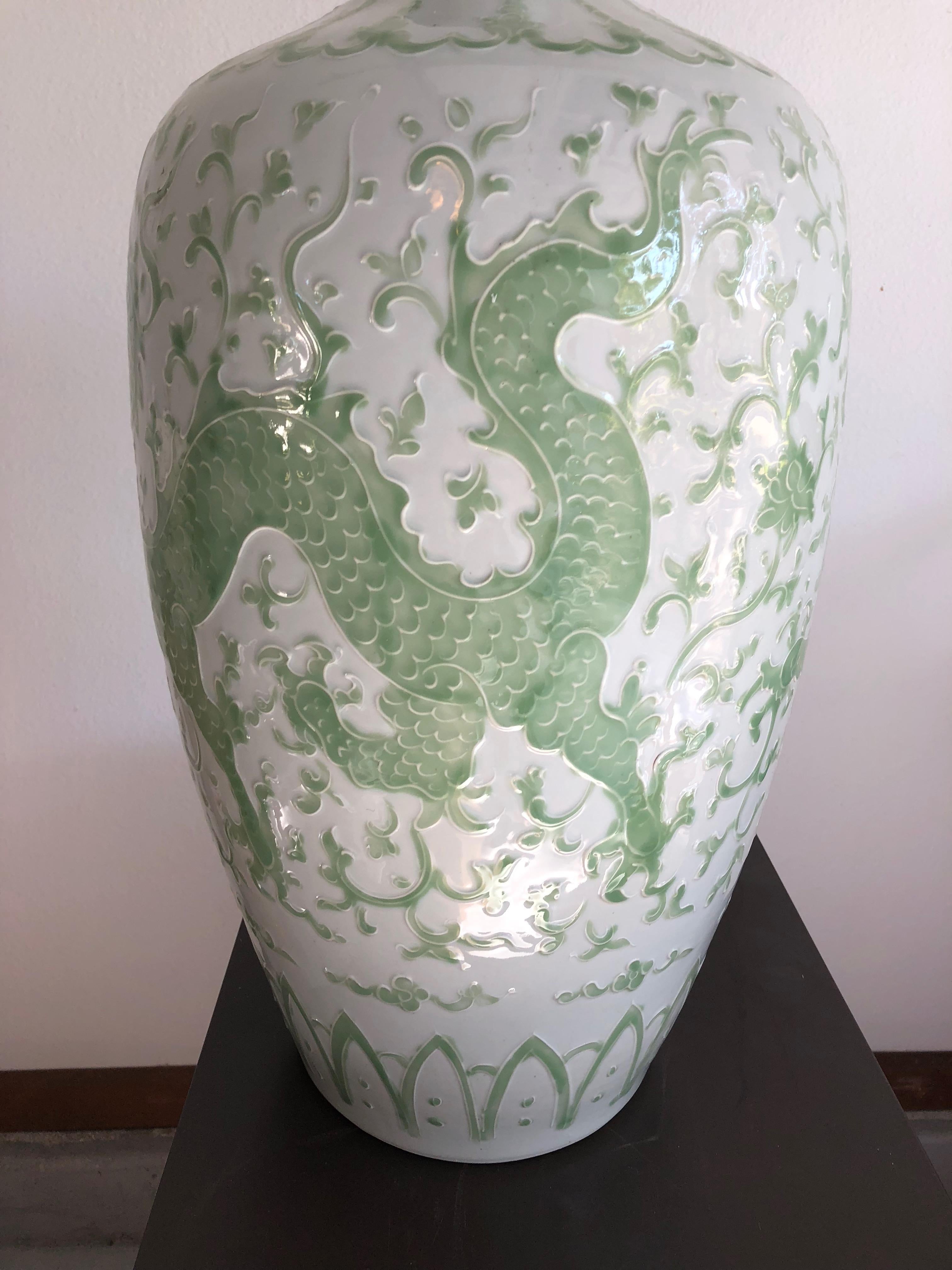 This pair of hand painted dragon vases are porcelain having a white background with pale green dragon design. Bulbous at top with small open rim. Large than normal.
