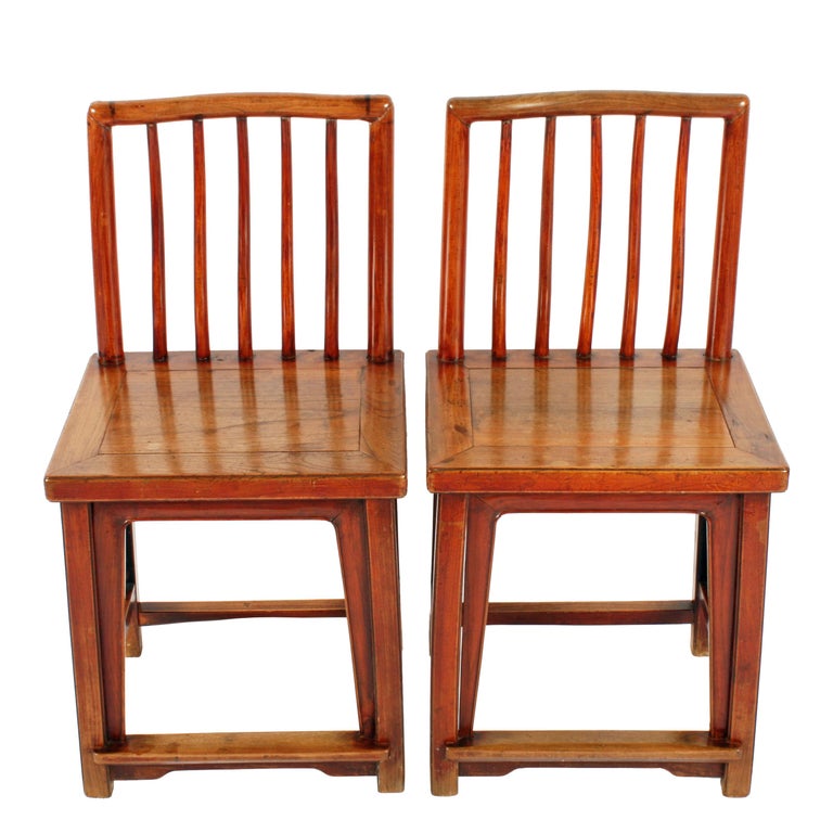 A pair of 19th century Chinese elm rose chairs.

The chairs are made from solid elm with a panel seat and square legs.

The back has five round spars inside a pair of uprights and a shaped top rail.

The chairs have stretchers between the legs