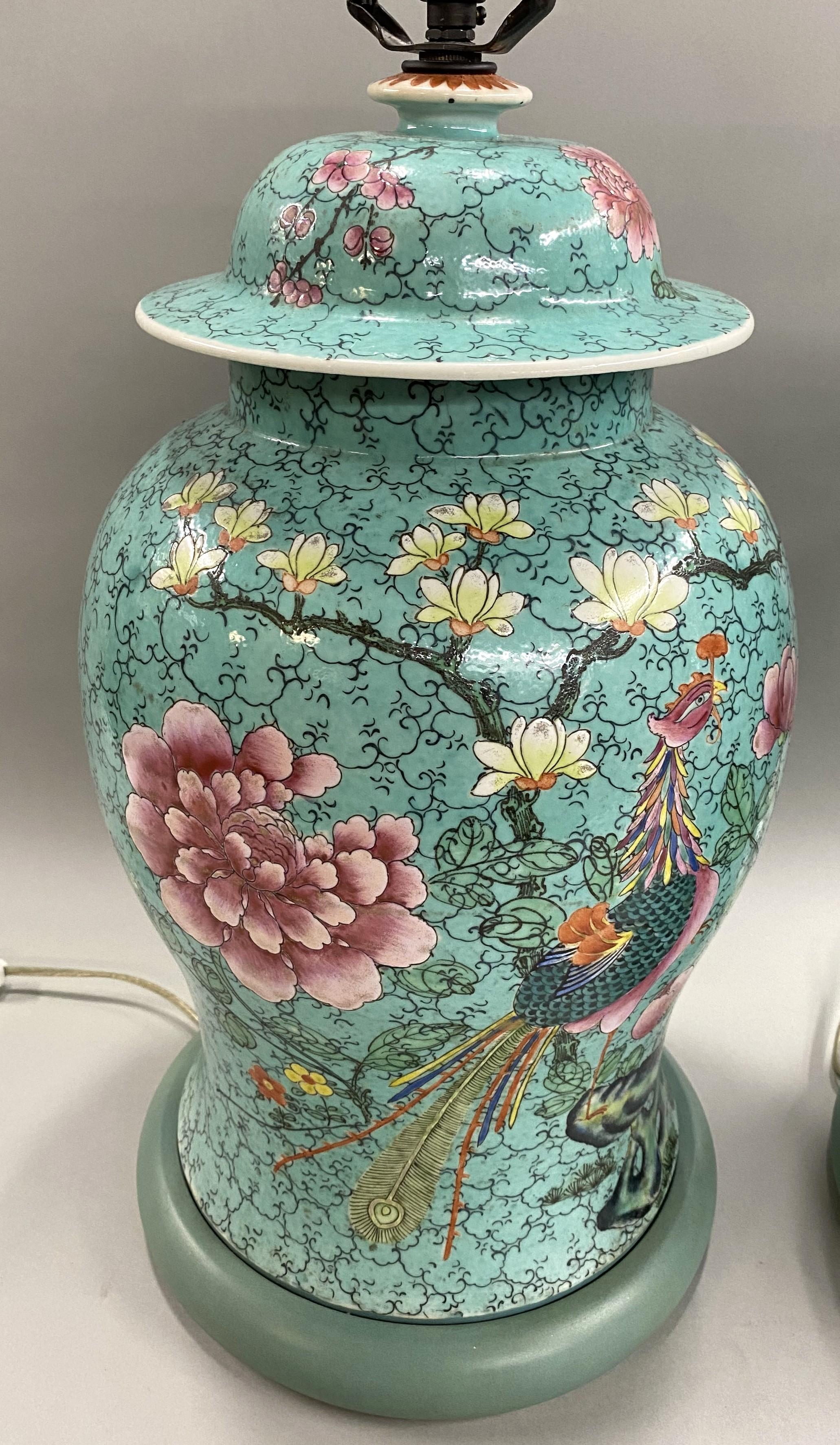 A beautiful pair of Chinese Export Famille Rose polychrome porcelain covered urns on a teal ground converted to single light table lamps, featuring hand painted bird, floral, and geometric decoration on custom painted wooden bases.  The urns