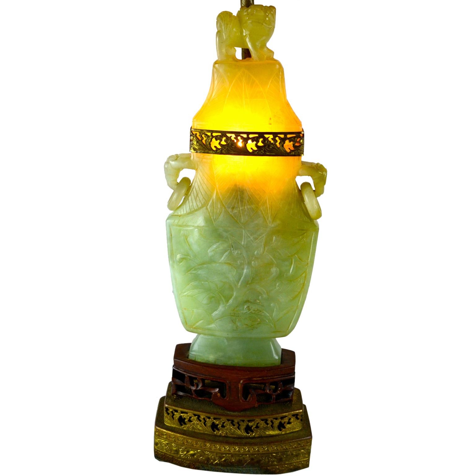 The stone bodies of this type of interior illuminated lamp are often referred to as quartz, jadeite or even jade but are in fact of the fluorite family, a softer stone more easily carved. The hollow urn bodies with ring handles are carved all around