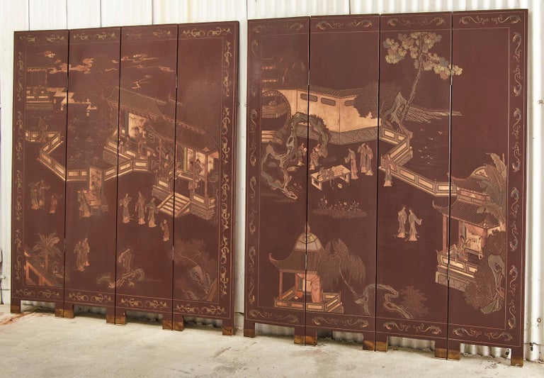 Pair of gorgeous faded red lacquer Chinese export four-panel coromandel screens. The screens depict a walled pagoda pavilion with figures engaged in leisurely activities amid lush trees. The panels feature incised lacquer having faded from dark red