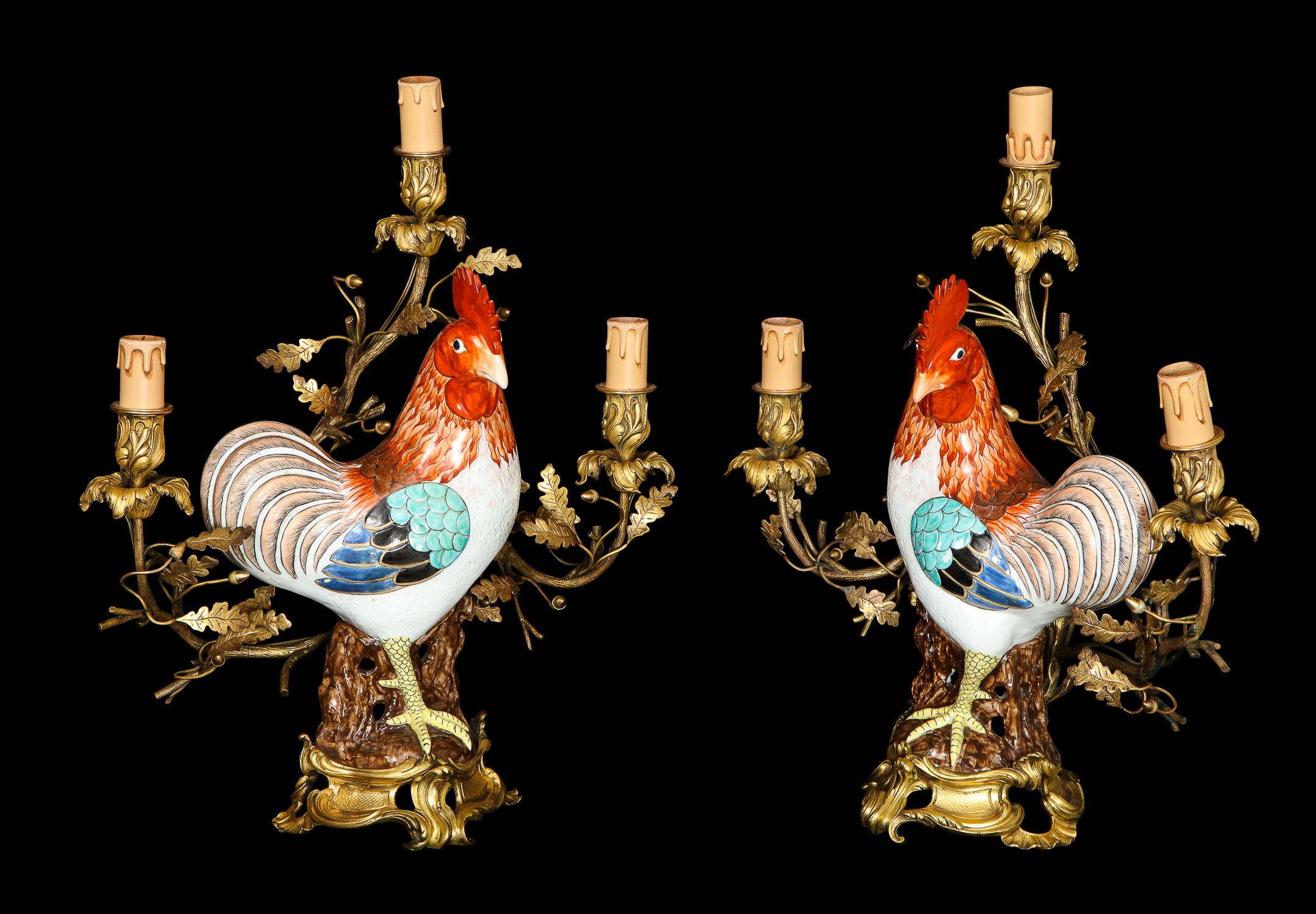 A pair of spectacular and large antique Chinese export porcelain rooster transitional Louis XV/Louis XVI style gilt bronze mounted three arm candelabra lamps of superb quality embellished with fine sculptures of multicolored Chinese export porcelain