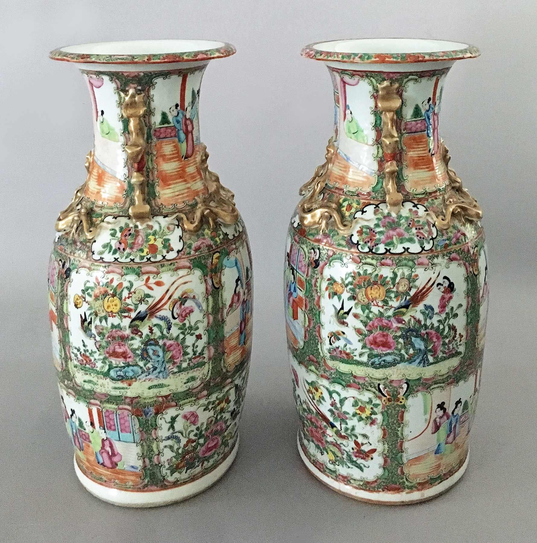 Pair of Chinese Export porcelain rose medallion tall open vases with applied gilded foo dog handles and dragons to neck and shoulder. The body is decorated with eight alternating panels of courtly figures and floral panels with peonies, exotic