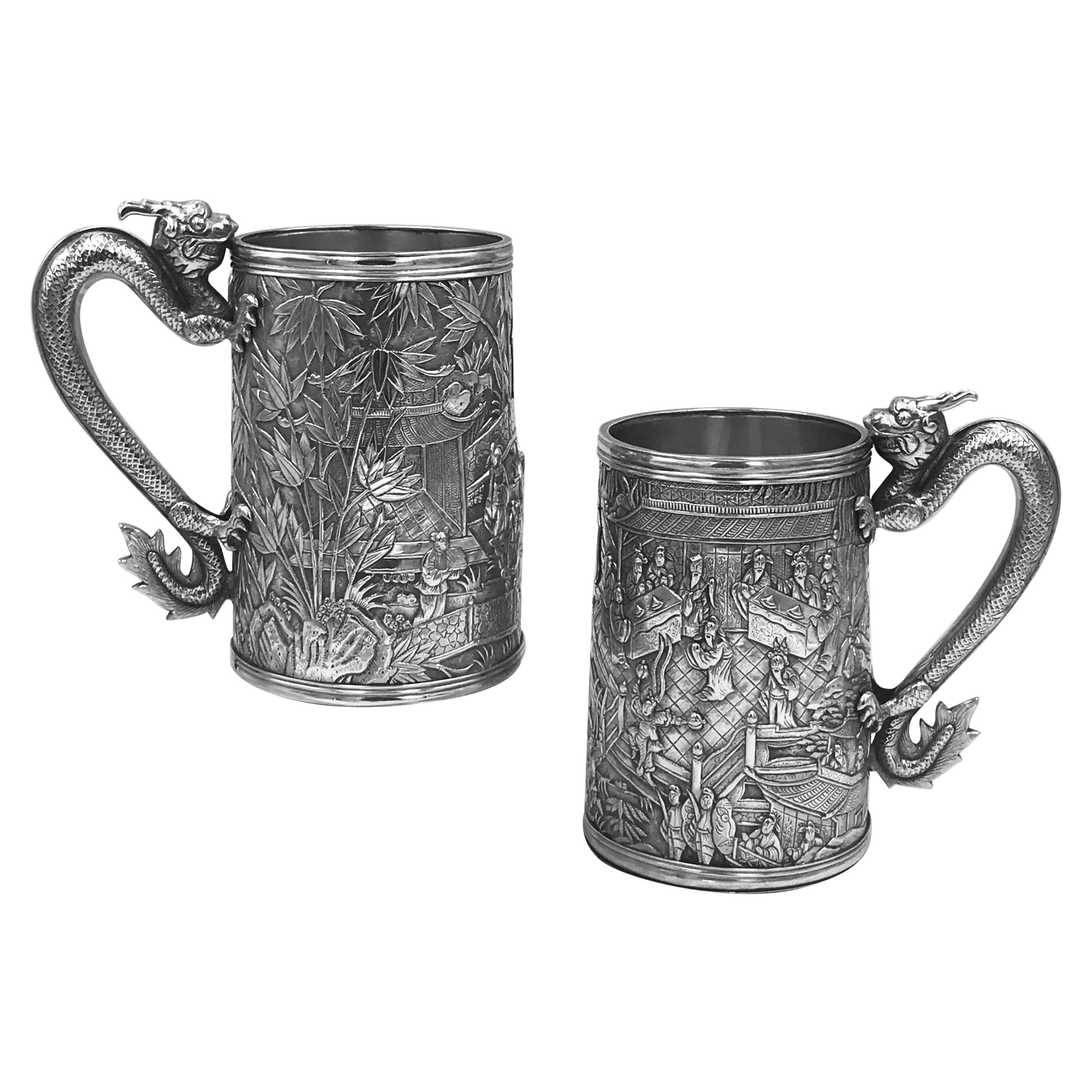 A rare pair of Chinese export silver mugs/tankards, each with figural Court scenes, bamboo, and dragon handles. They have the mark for Hoaching of Canton, circa 1860, and the Chinese character mark of the maker, Yi Chang.