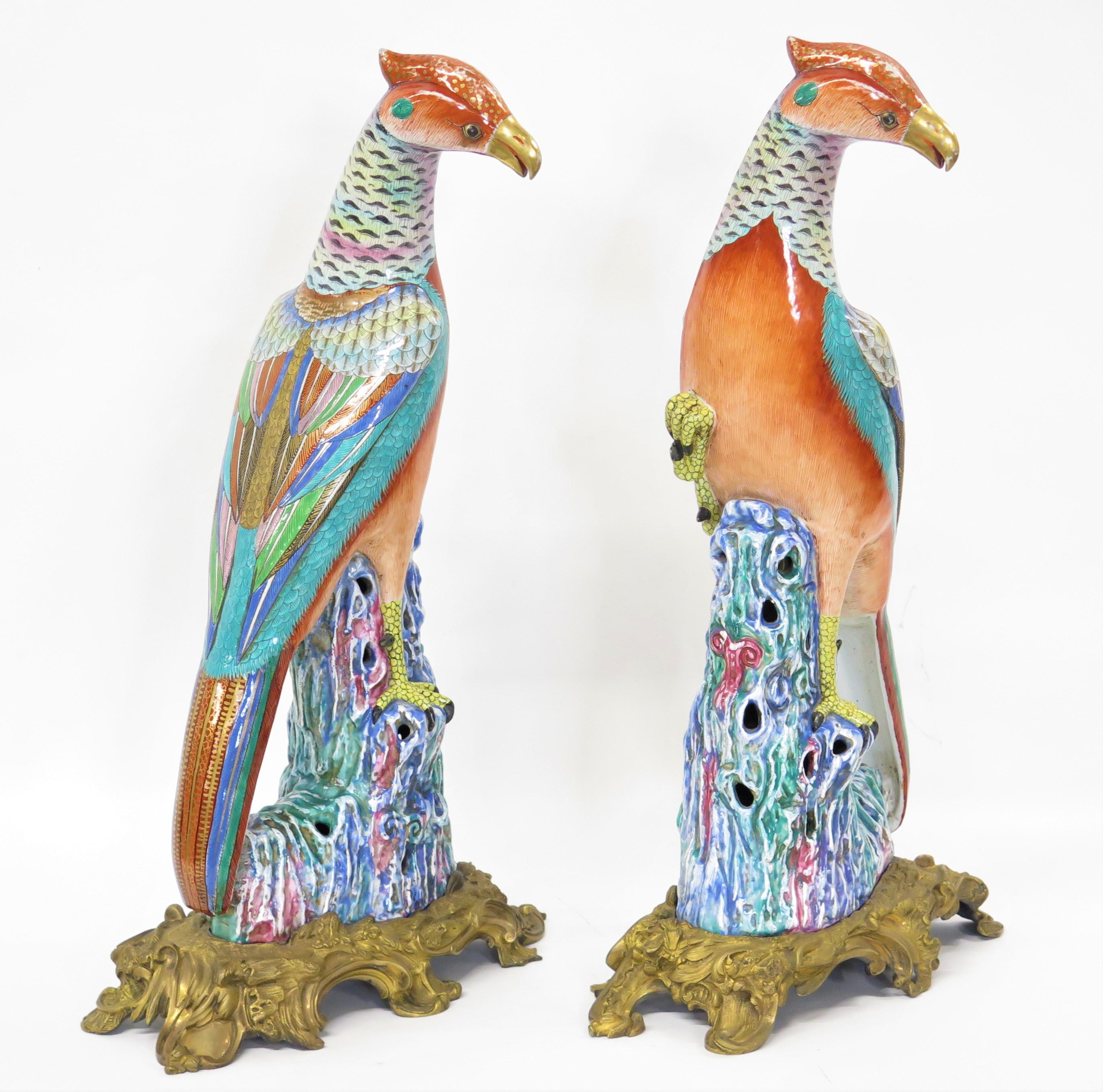 pair of French gilt bronze / ormolu-mounted Chinese Export style porcelain pheasants, splash-glazed rockwork in mirror image, their heads alertly cocked, the plumage on their long necks and folded wings picked out in vibrant Famille Rose enamels,