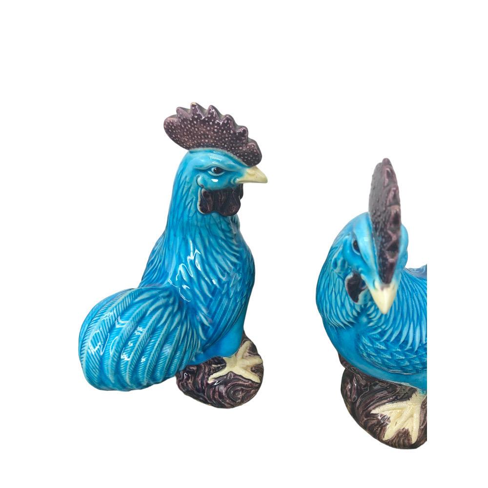 Pair of Chinese Export Turquoise Glazed Roosters. The roosters are made of fine porcelain, and are glazed in a vibrant turquoise color. They are decorated with intricate details, such as their feathered tails and combs. The roosters are perched  on