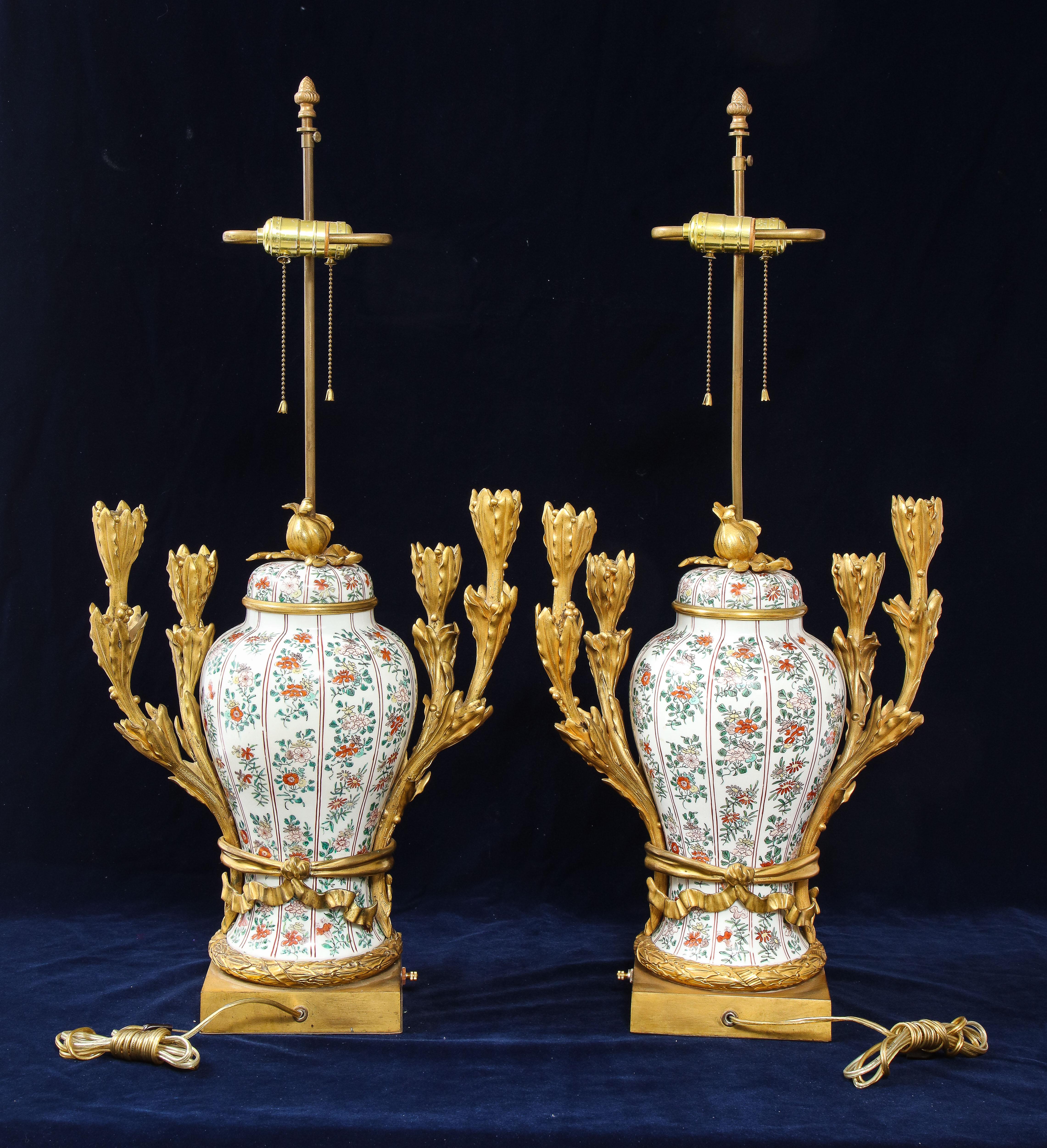 Magnifica coppia di lampade a candelabro in porcellana cinese da esportazione del XIX secolo con montatura in ormolu e decorazioni floreali in smalto Famille Vert. Ogni vaso è a forma di balaustro con coperchio a cupola, sormontato da un terminale