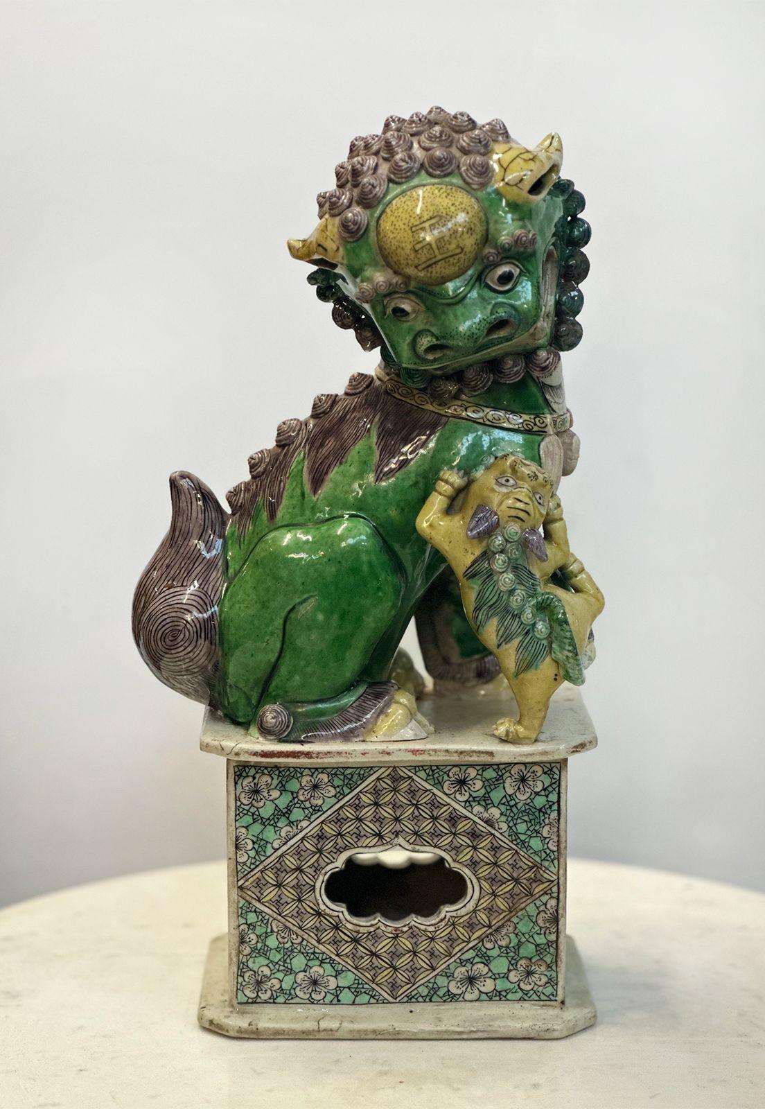 Pair of traditional Chinese Famille Verte male and female Buddhist lions belonging to the Kangxi period (1661-1722). Each stands on a plinth, one with its head to one side and having its jaw open, it holds a small cub. The other holds a traditional