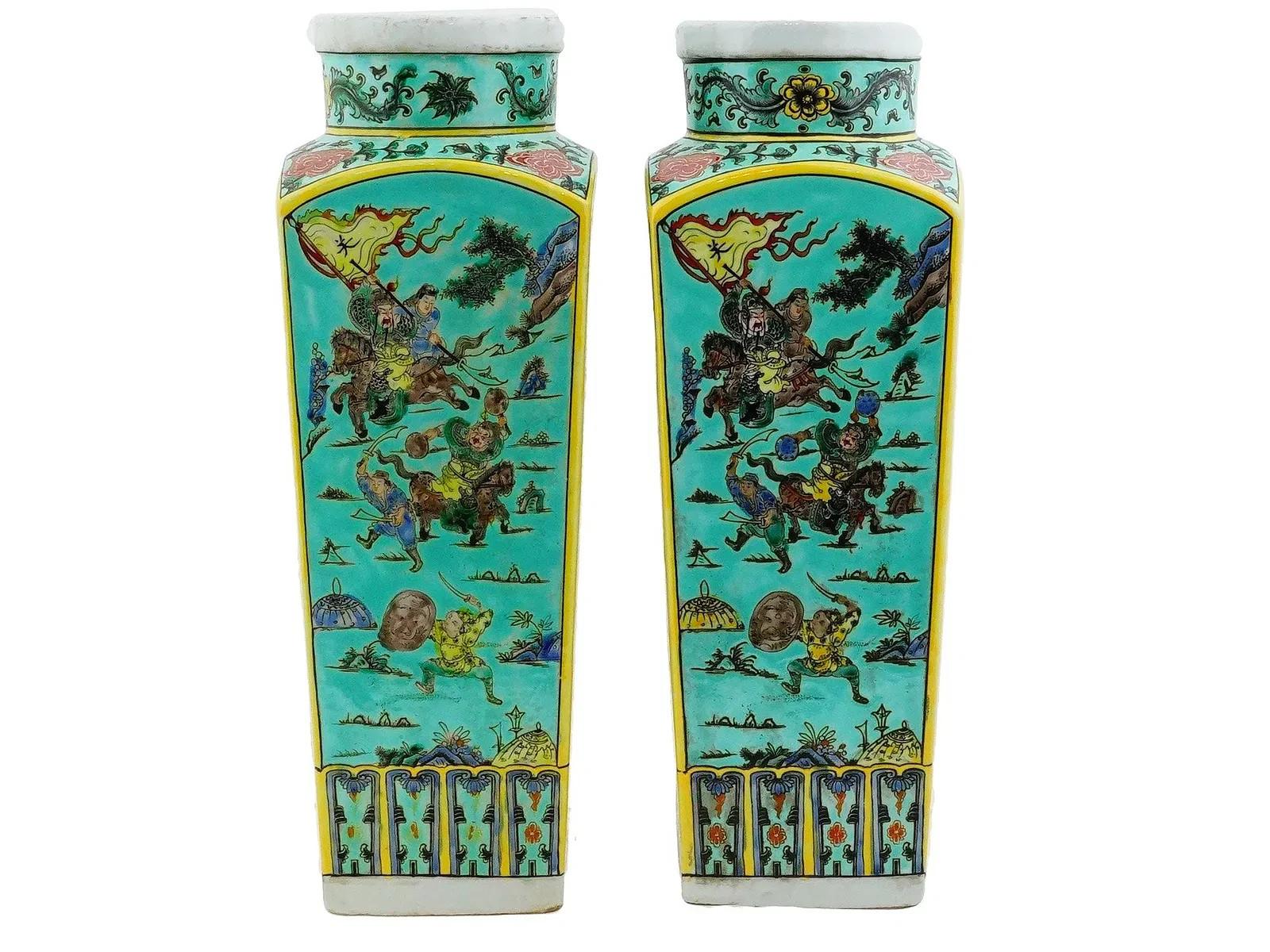 A pair of Chinese Famille Verte porcelain vases. Each vase has an unusual shape, and adorned with an enamelled design representing battle scenes. The necks and the bases of the vases are adorned with floral, foliage, scrollwork and geometrical