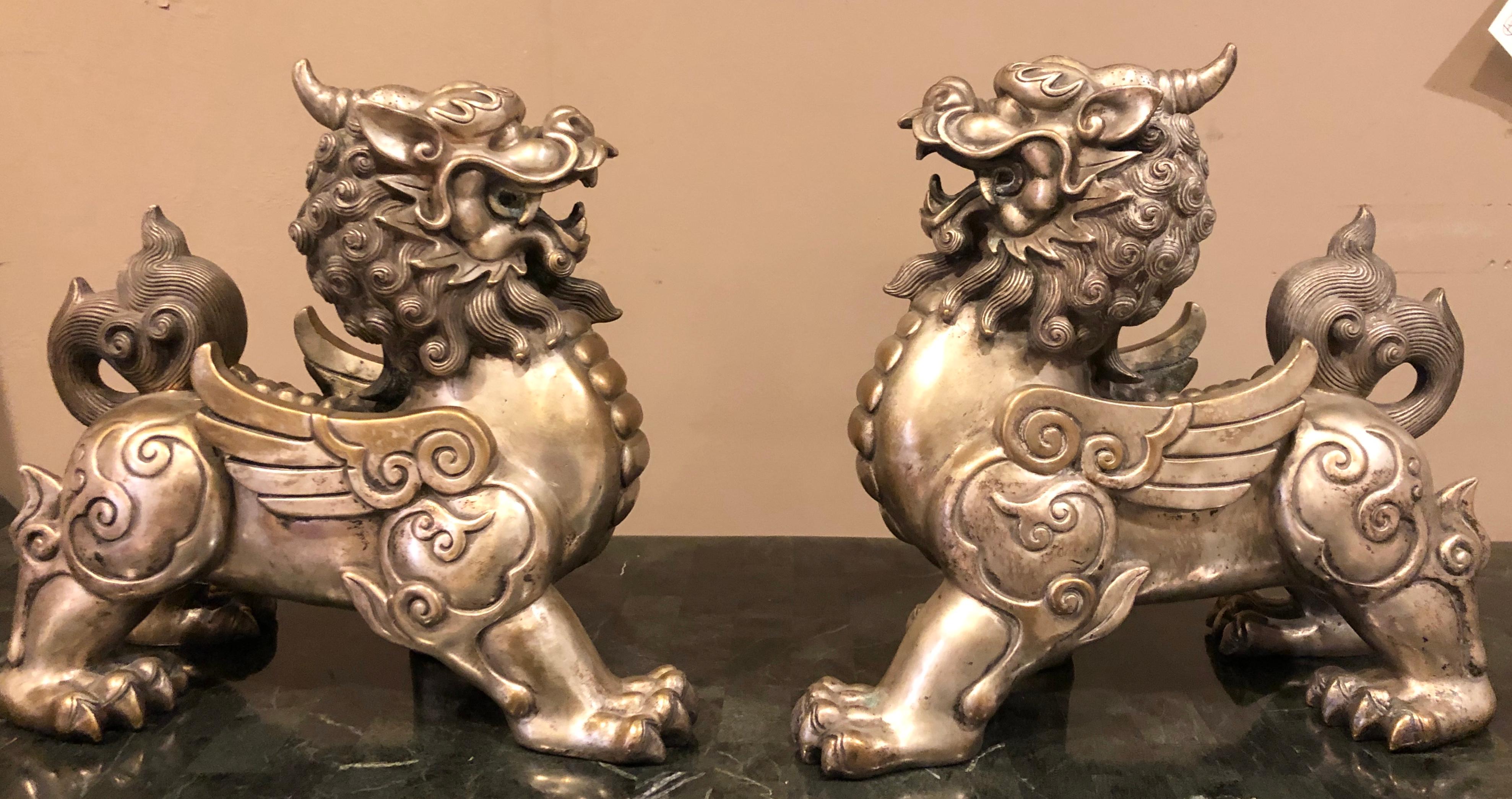 Pair of Chinese foo dogs. Bronze silver plated solid heavy decorative foo dogs. These large and impressive guardians of the home are certain to spark conversation. These finely cast silver placed sculptures are finely detailed as they oppose each