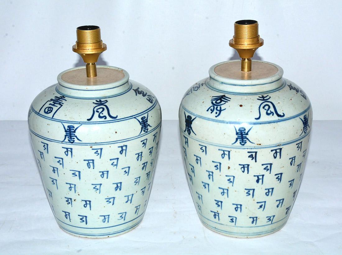The pair of blue-and-off-white Chinese ginger jar lamps have Chinese characters as decoration. Simple and Classic at the same time. The fixtures are made for European shades which we can change for you if needed. Wired for US use.