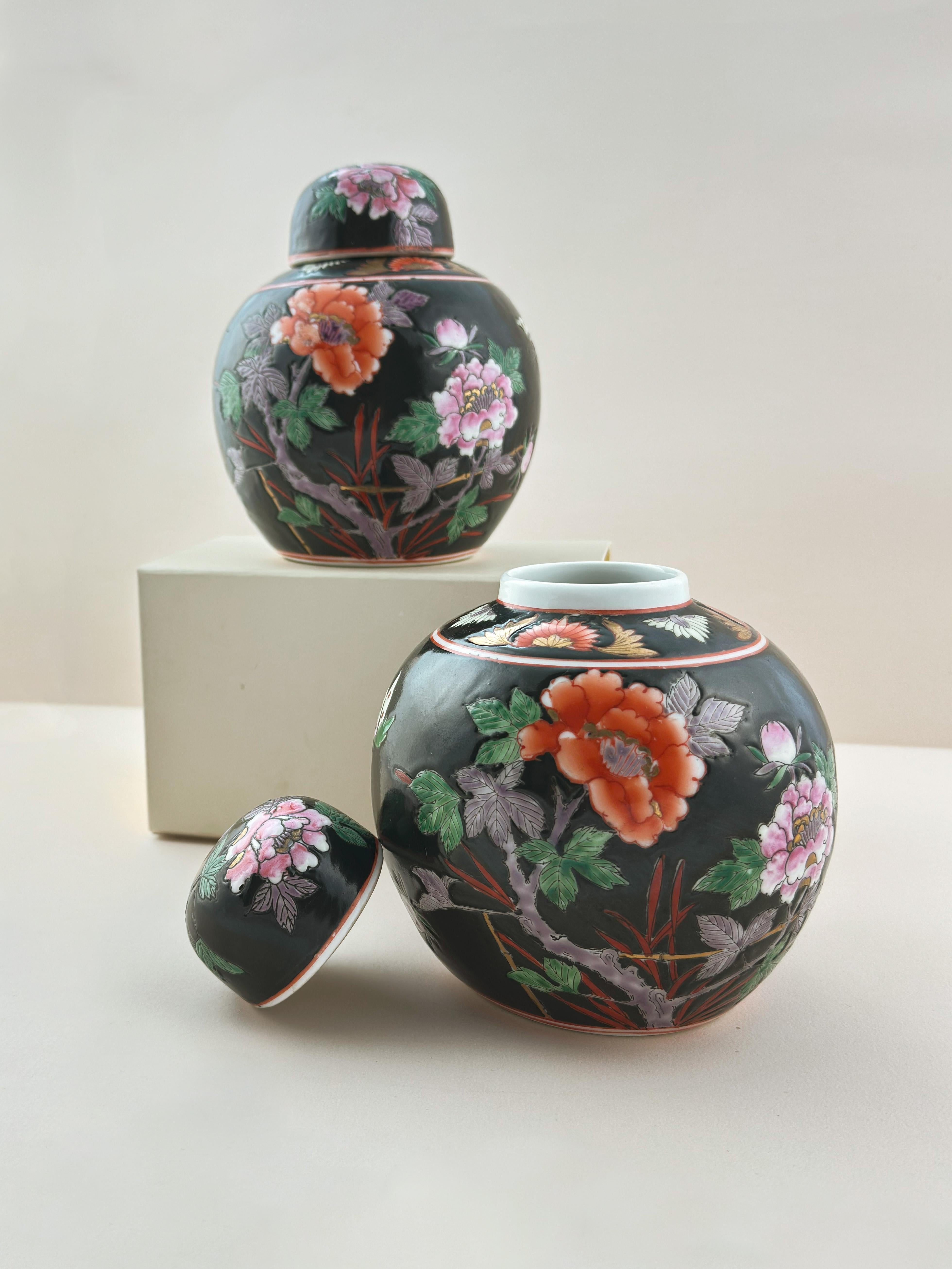 Pareja a juego de tarros de jengibre de porcelana china vintage, fabricados a mano en la década de 1960 y decorados en estilo Famille Noire.

Cada jarra presenta una audaz escena figurada Famille Noire que envuelve el rotundo cuerpo de la pieza.