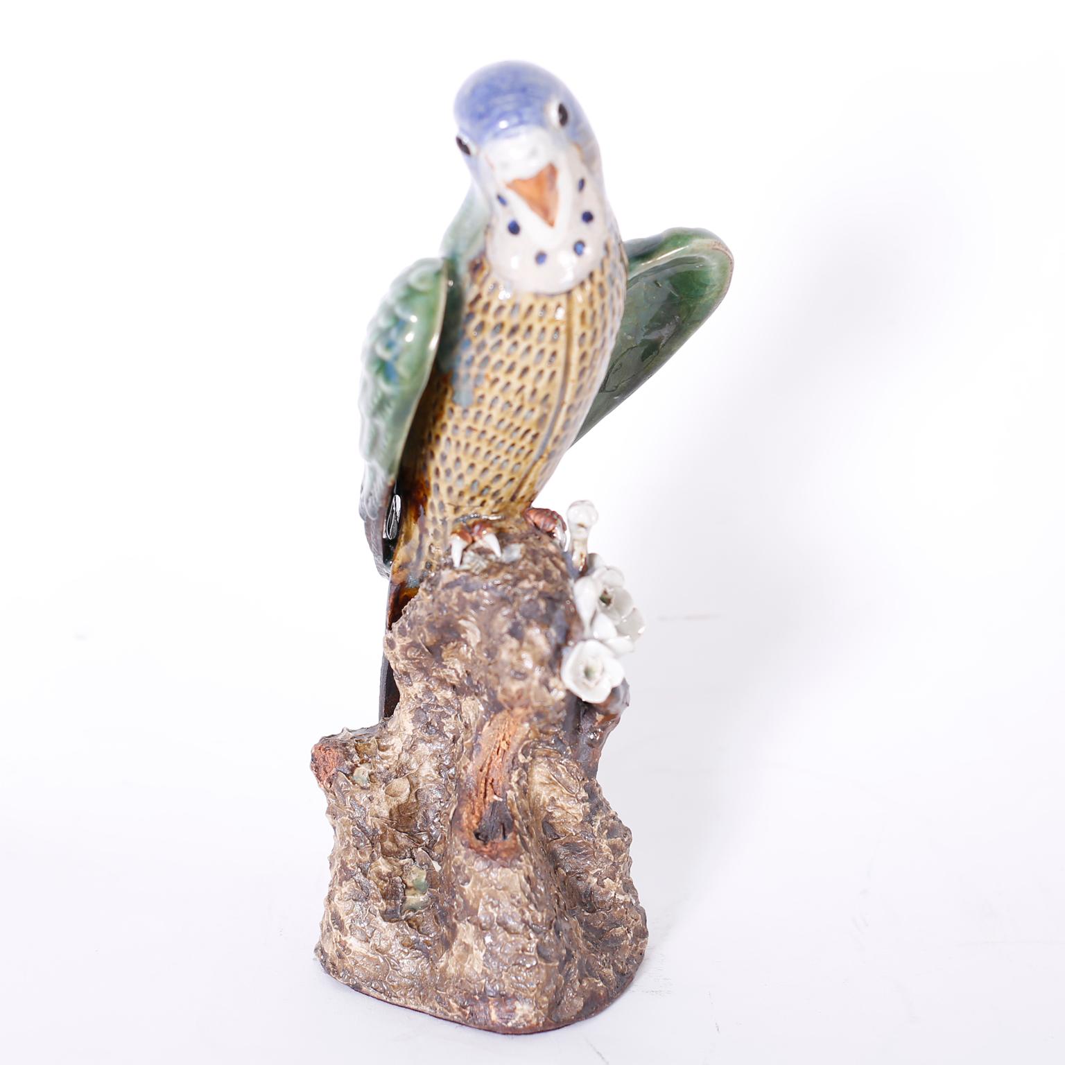 Charming pair of Chinese parakeets or budgies crafted in terra cotta, decorated, glazed and perched on tree trunks with flowers. Signed with chop marks on the bottoms.