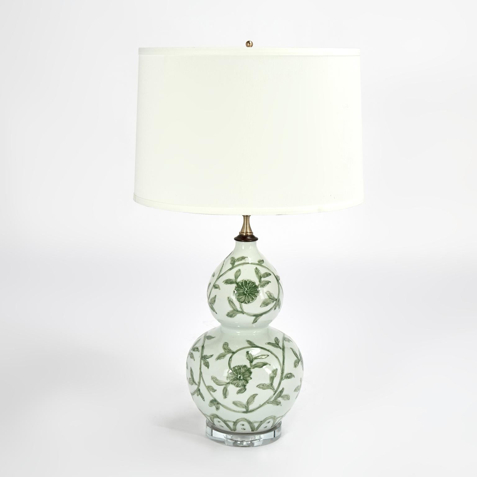 Lofty pair of Chinese porcelain table lamps handcrafted in classic double gourd form, hand decorated with green floral designs and presented on lucite bases. 