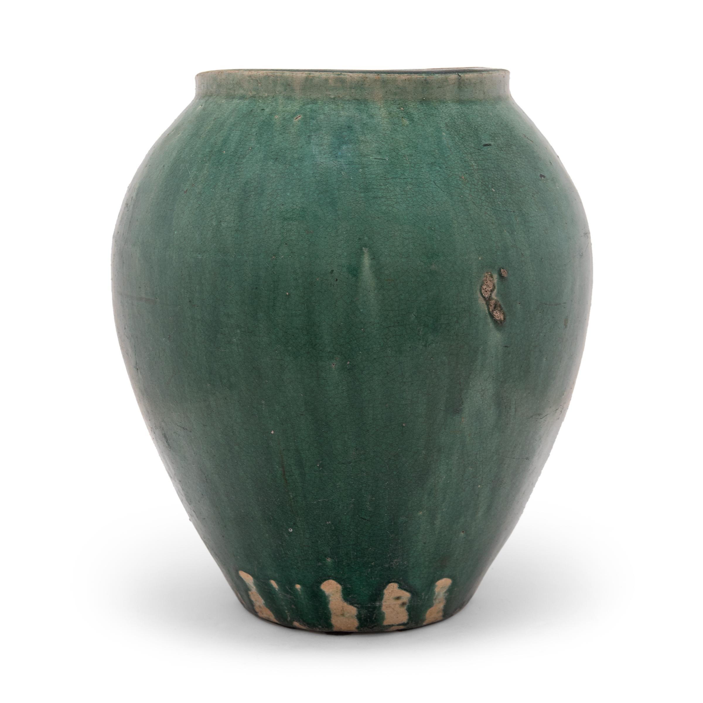 A luminous blue-green glaze sheets, pools, and drips down the tapered sides of these elegant stoneware jars, lingering on every imperfection. The glassy glaze exhibits a rich range of colors and crazed during firing for a beautiful crackled finish.