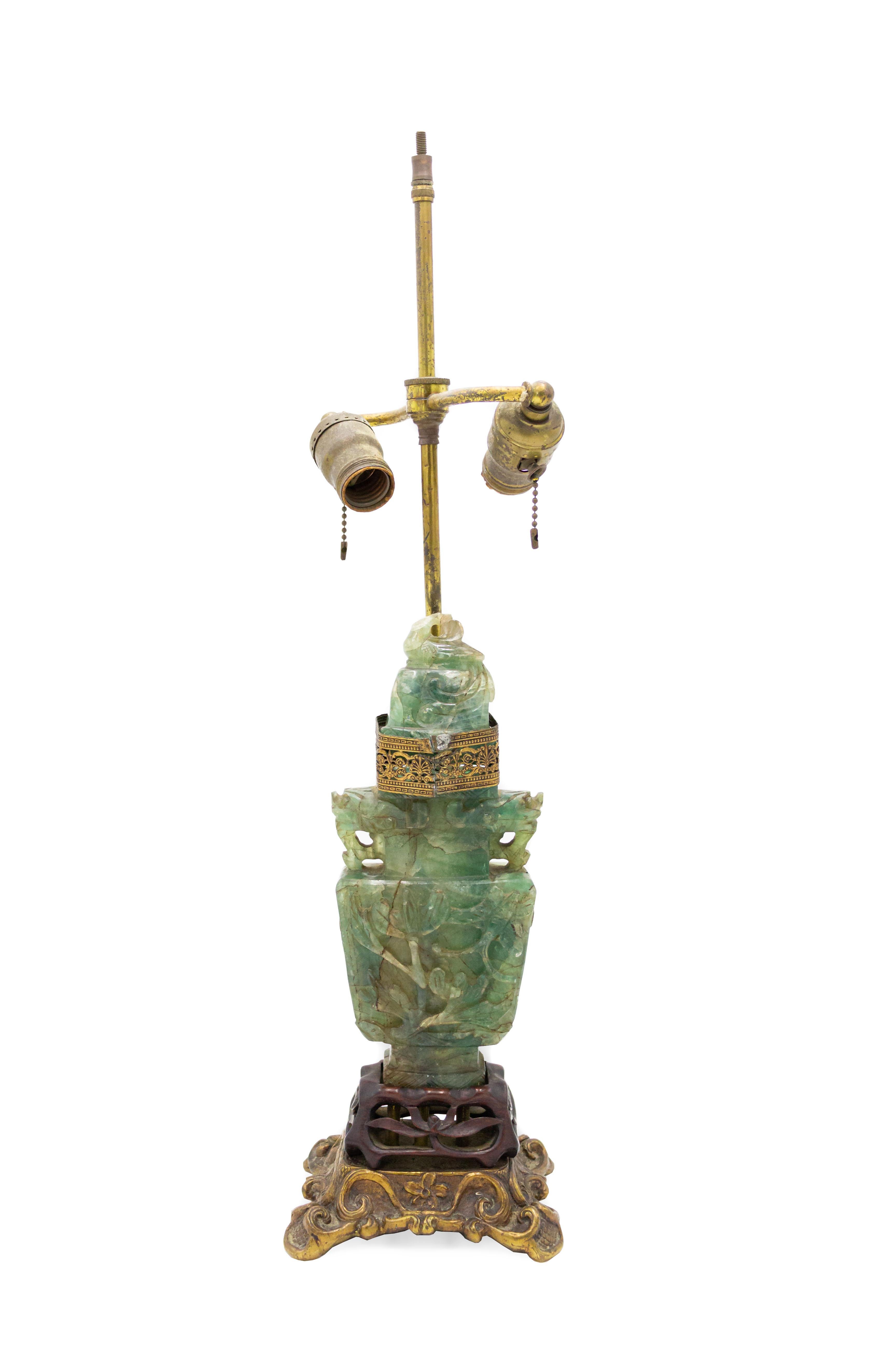 Pair of Chinese jade-colored hardstone lamps with carved teak and gilt metal bases and pierced gilt metal trim with a decorative motif.