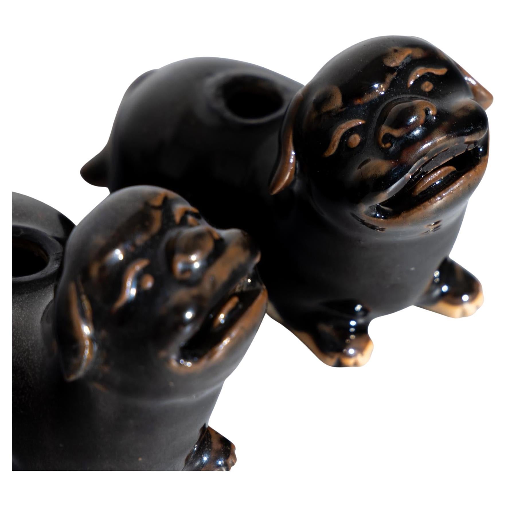 Pair of small Chinese guardian lions or Foo Dogs made of dark brown glazed ceramic. The lions have a round opening for pen holders in the back. A pair of friendly faces waiting to guard the workplace.