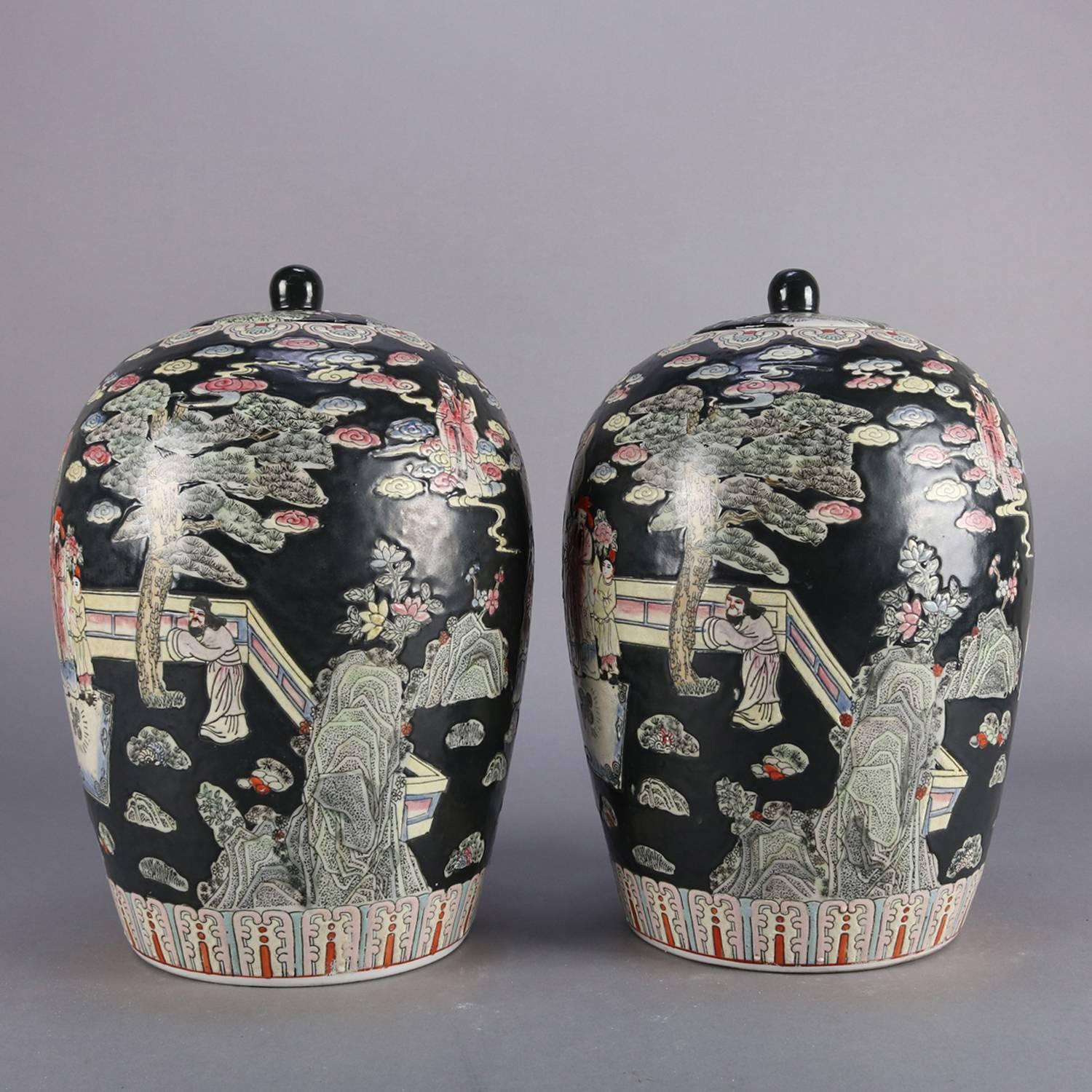 Pair of Chinese hand-painted porcelain covered jars with all-over decoration of garden scene with figures and stylized patterned bordering, 20th century.

Measure: 14