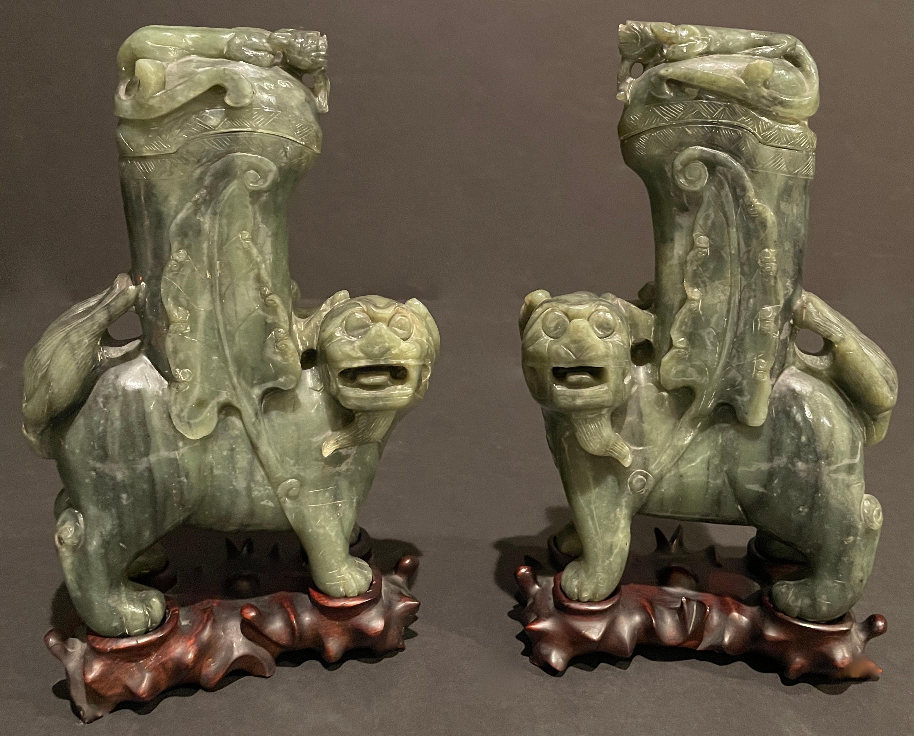 Paire de Lions Foo ou Chiens Fu en jade chinois sculpté à la main. Cette paire de jade épinard chinois semble être une néphrite. Les vases couverts ont un motif de lion foo figuratif avec des motifs de plumes de queue de phénix en relief. Je pense