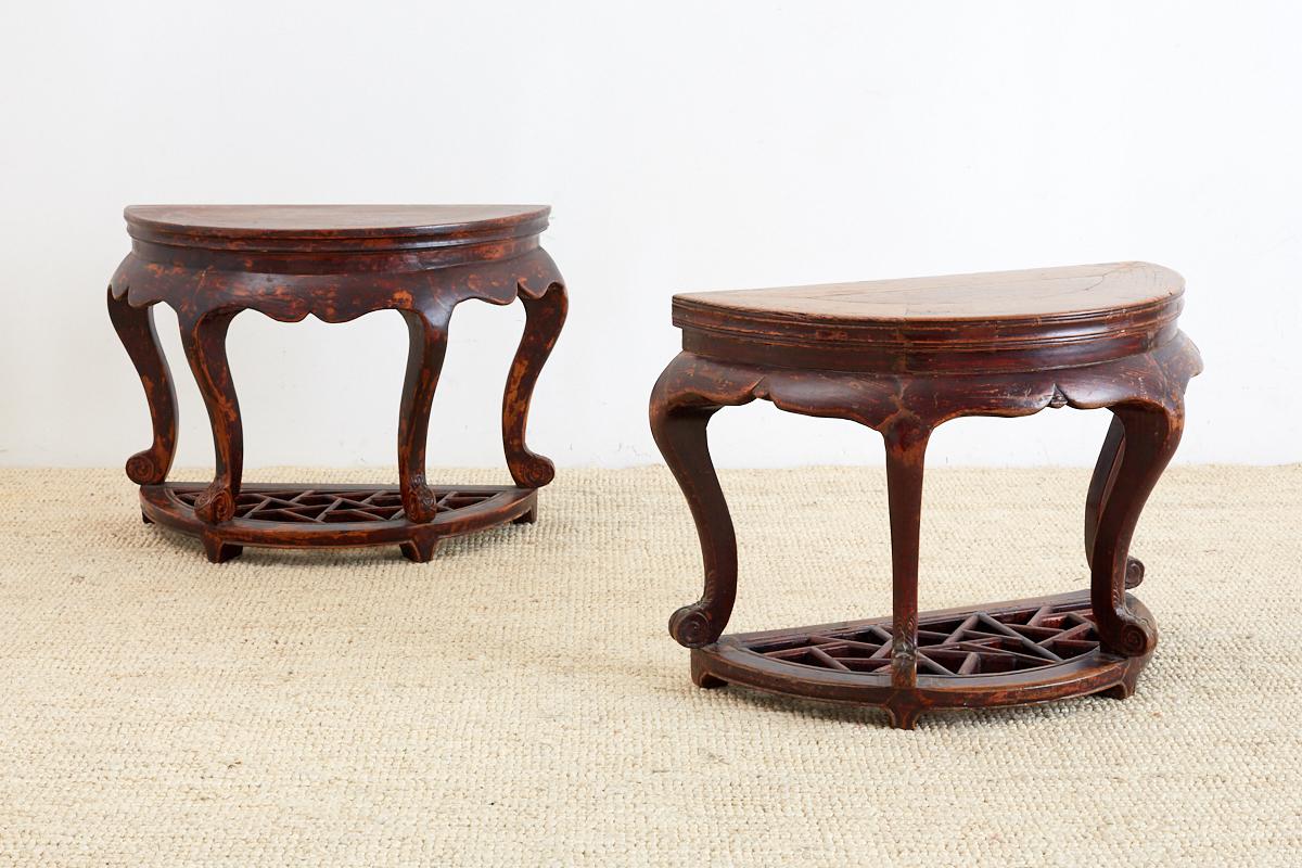 Handsome pair of Chinese hardwood carved side tables or end tables having a demilune form. Each four legged table is mounted to a conforming base with a decorative cracked ice motif lattice insert. The tables have beautiful cabriole legs with