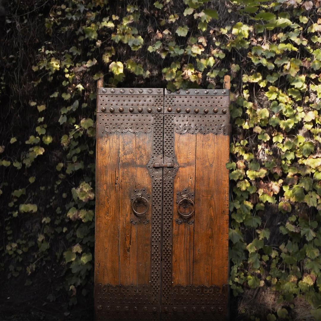 This impressive set of doors dates to the mid-19th century and originated as the outermost entrance gate to a traditional Qing dynasty courtyard home. Crafted of Northern elmwood (yumu) and hand-worked iron, this rustic door has developed a rich