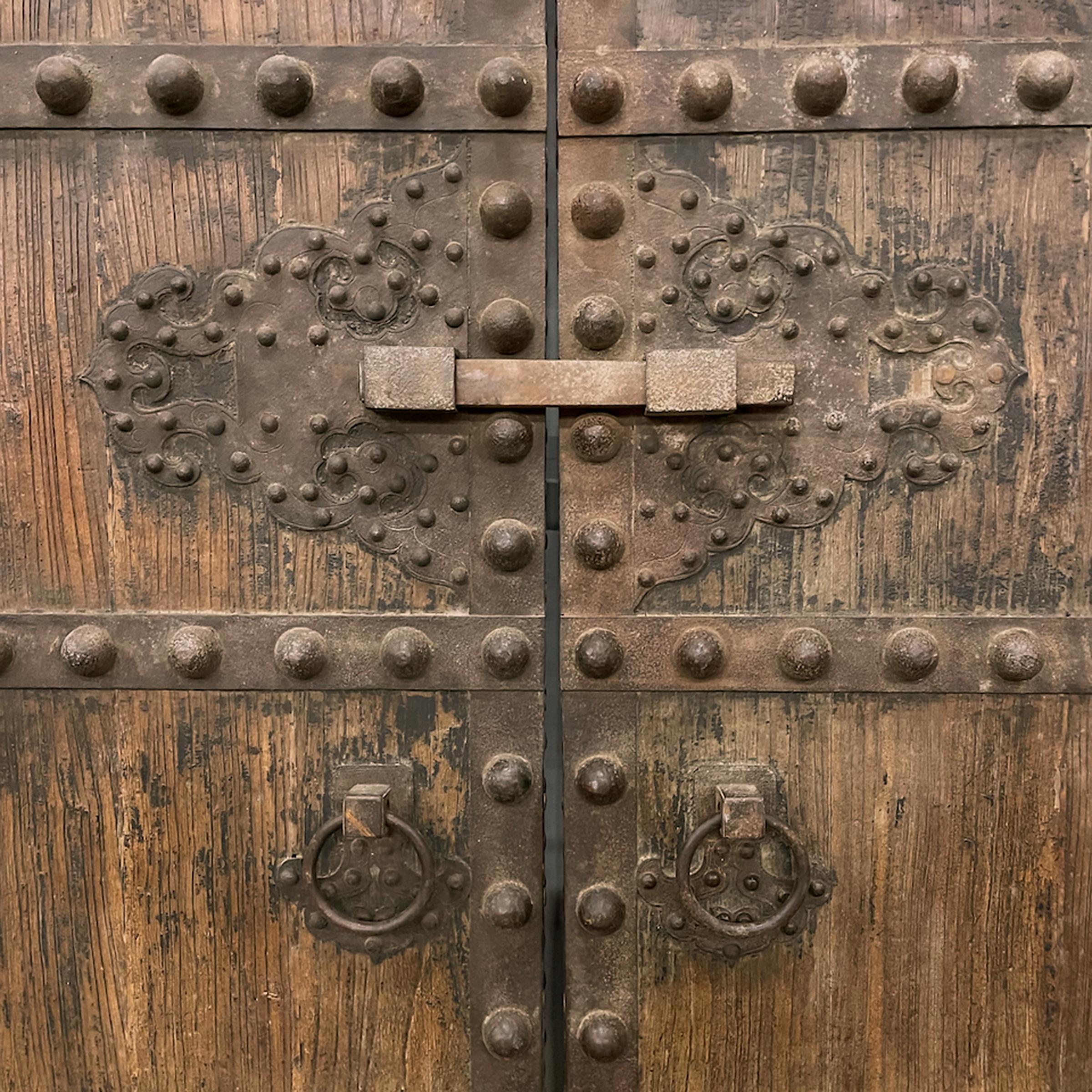 This impressive set of doors dates to the turn of the century and originated as the outermost entrance gate to a traditional courtyard home in northern China. Crafted of locust wood and hand-worked iron, the rustic doors have developed a fantastic