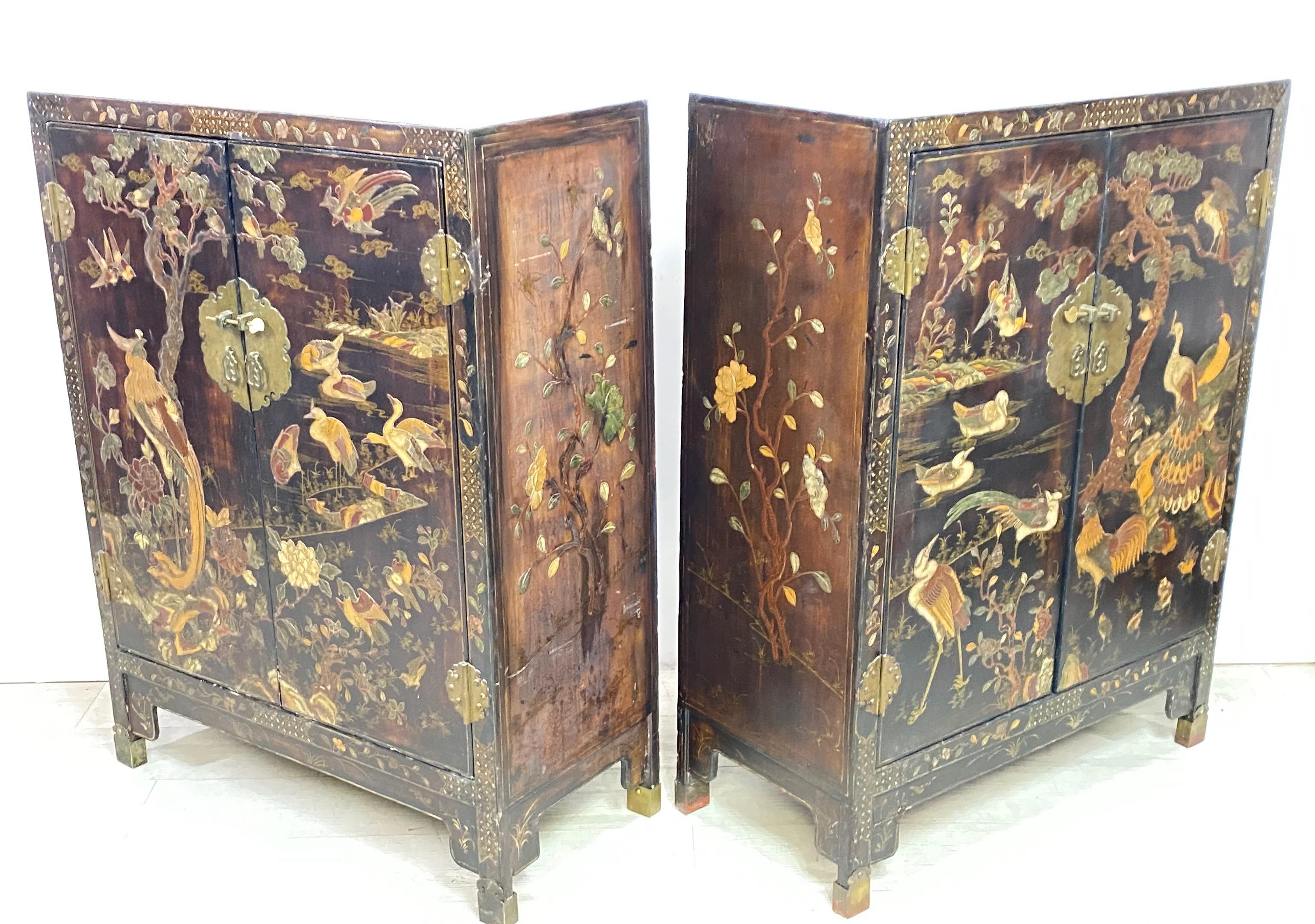 Excellent pair of Chinese lacquered cabinets or nightstands decorated with hardstone and mother of pearl carvings of flora and fauna. These dark brown chests are matching in size and fronted by two doors with patinated brass metal lockplates and