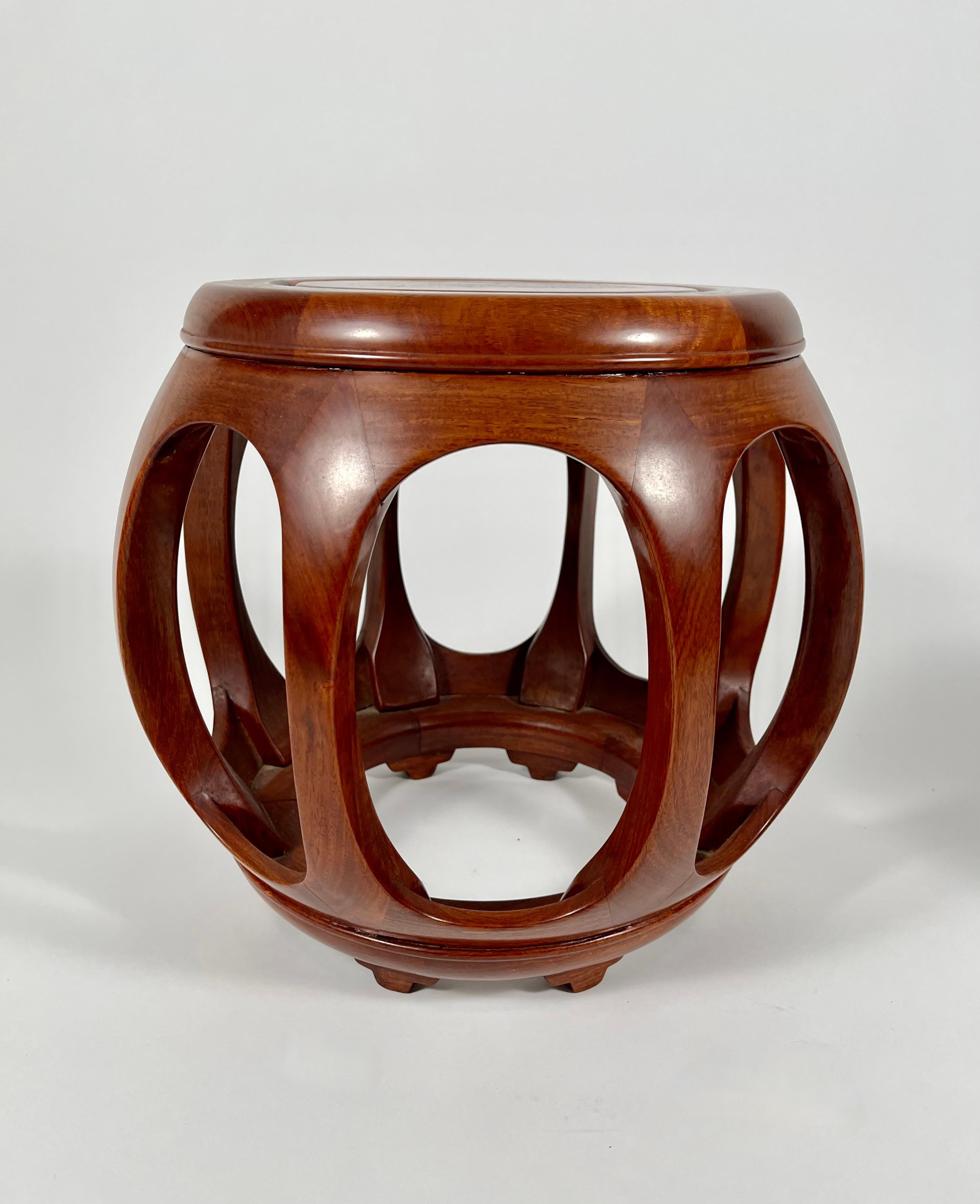 A fine quality pair of Chinese hardwood melon-form stools, ideal as small drinks tables, each of barrel form with inset circular top supported by semi-circular legs raised on a ring-form base with shaped feet. Beautiful rich color and solid