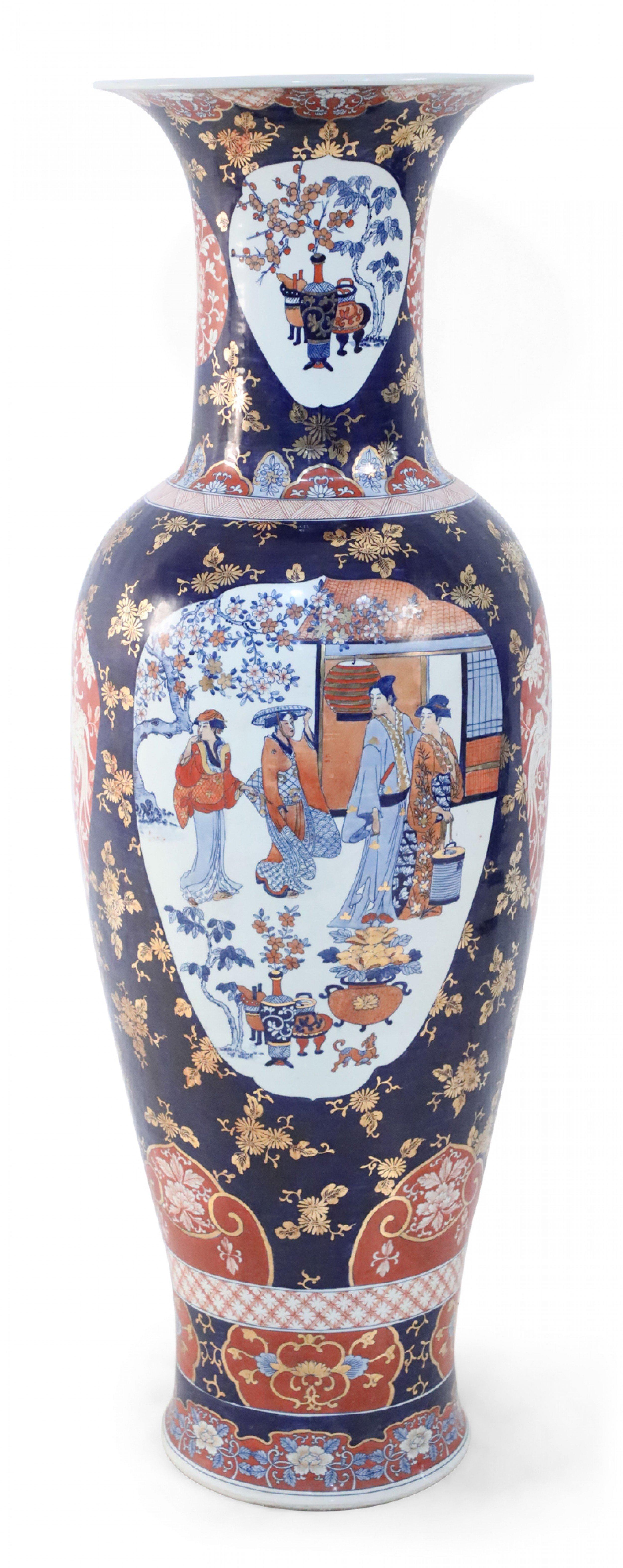 COPPIA di vasi monumentali cinesi in porcellana blu e oro con motivi floreali che ricordano la ceramica giapponese Imari sia per la tavolozza che per il design, con una scena centrale di donne in un giardino affiancata da medaglioni arancioni