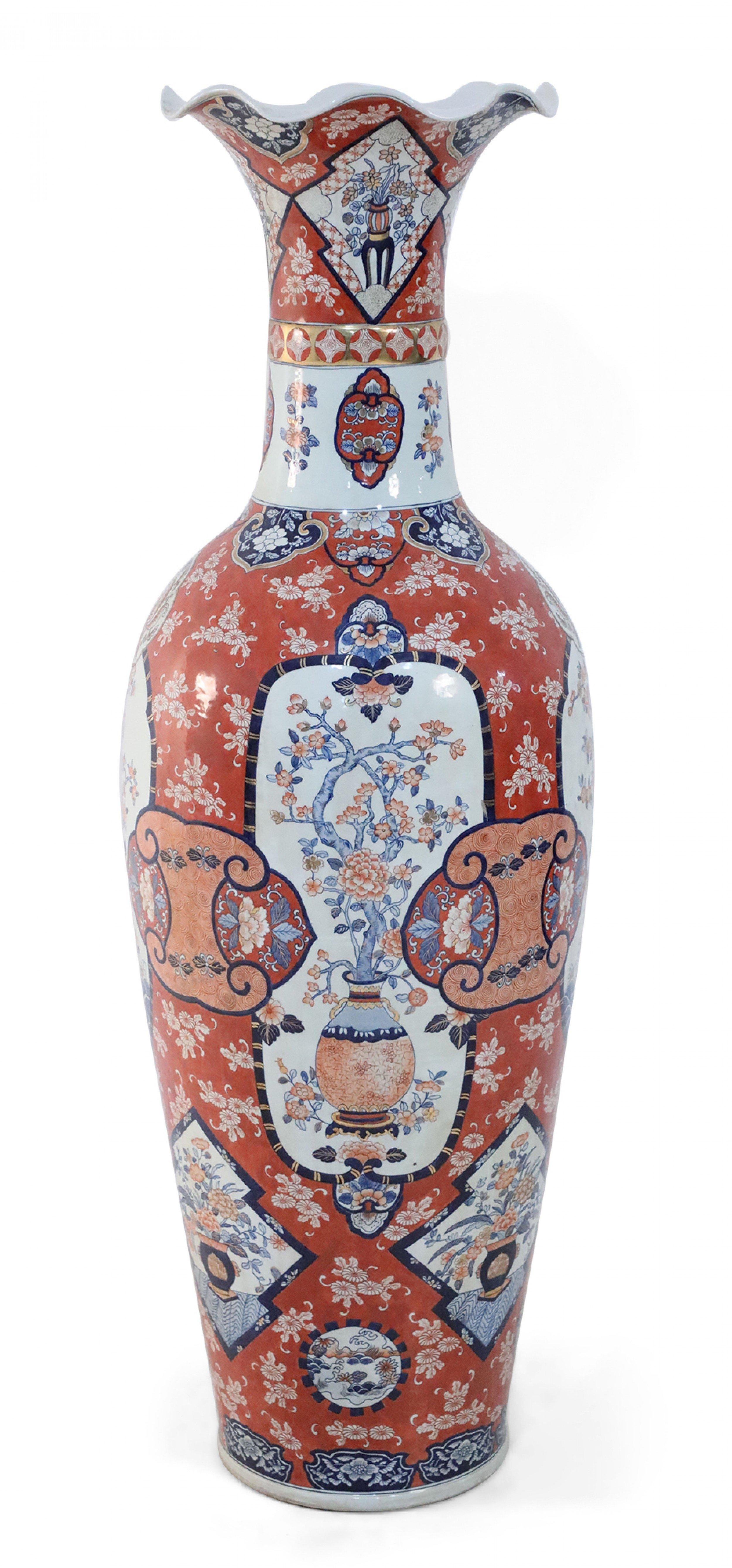 COPPIA di vasi da terra cinesi monumentali in porcellana che celebrano l'Imari giapponese sia nella tavolozza che nel design, con motivi floreali bianchi, blu, arancioni e oro su fondi color ruggine e aperture scanalate e smerlate (PREZZO A