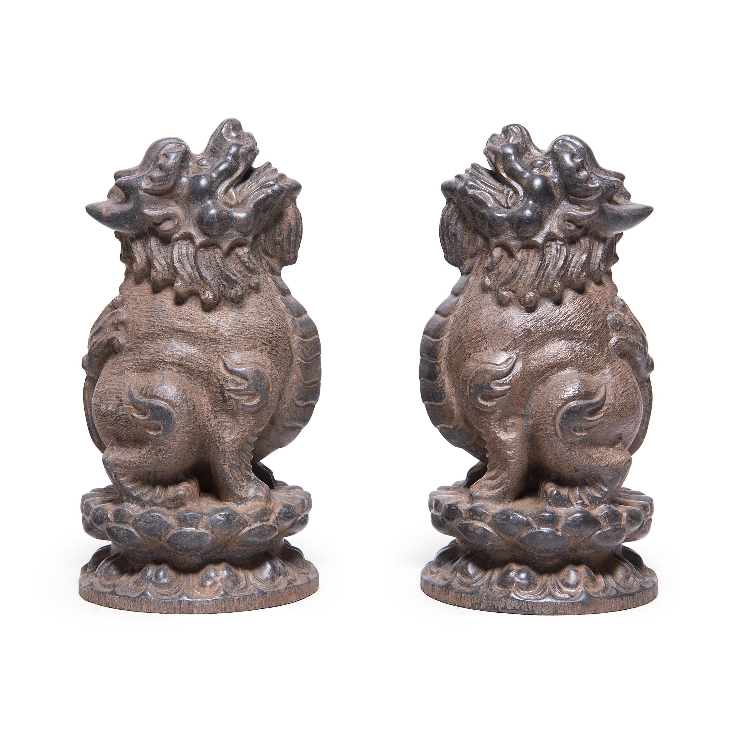 Hand-carved from solid limestone, these mythical figures are qilin, hybrid creatures from Chinese mythology thought to bring luck and happiness. Crouching upon lotus plinths, these qilin are sculpted with lion-like features, though with the head of