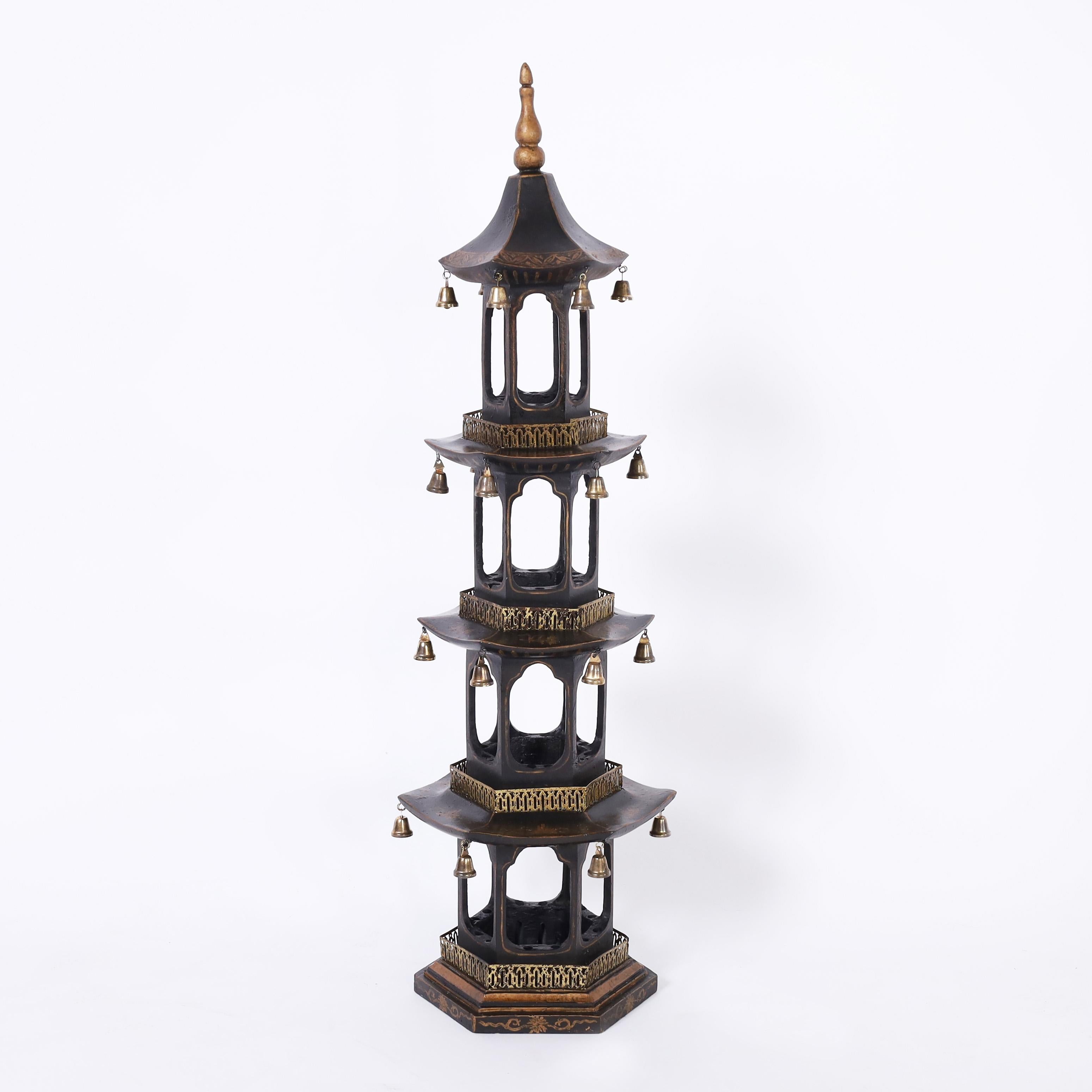 Striking pair of four tiered pagoda towers crafted in composition with a black lacquer finish decorated with gold painted floral designs, brass balconies, and bells.
