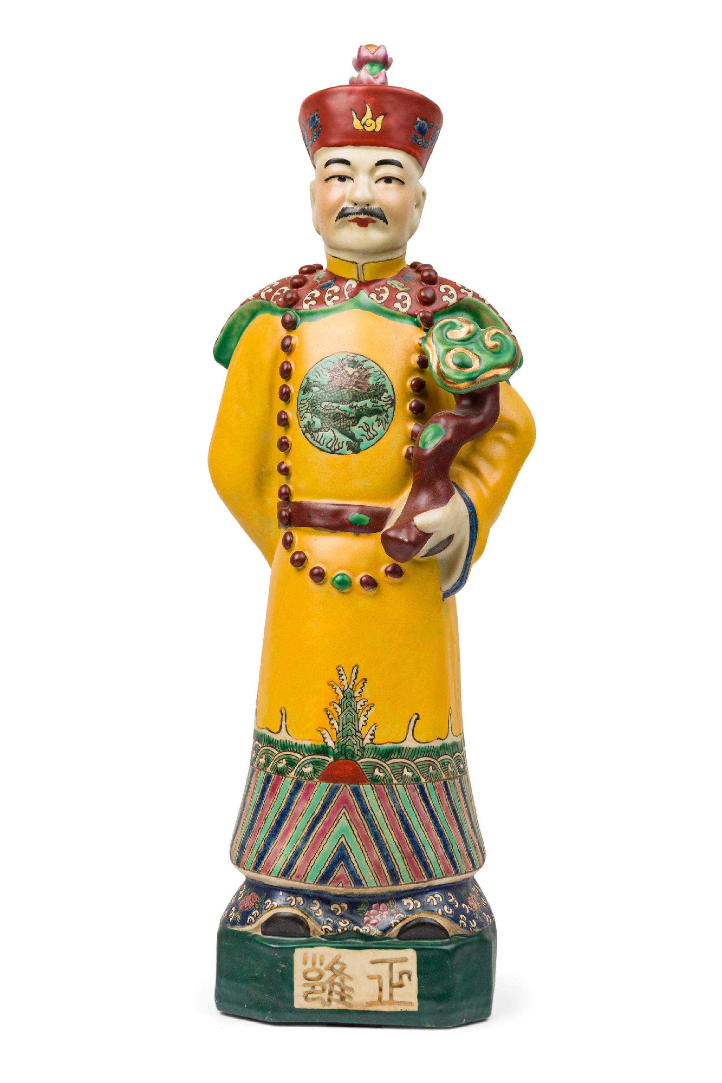 PAIR of Chinese painted ceramic identical figures in a matte glaze, depicting a mustached, hatted emperor in a formal elaborate yellow robe with dragon medallion, his left arm cradling a lingzhi ruyi, his right arm positioned behind his back. He is