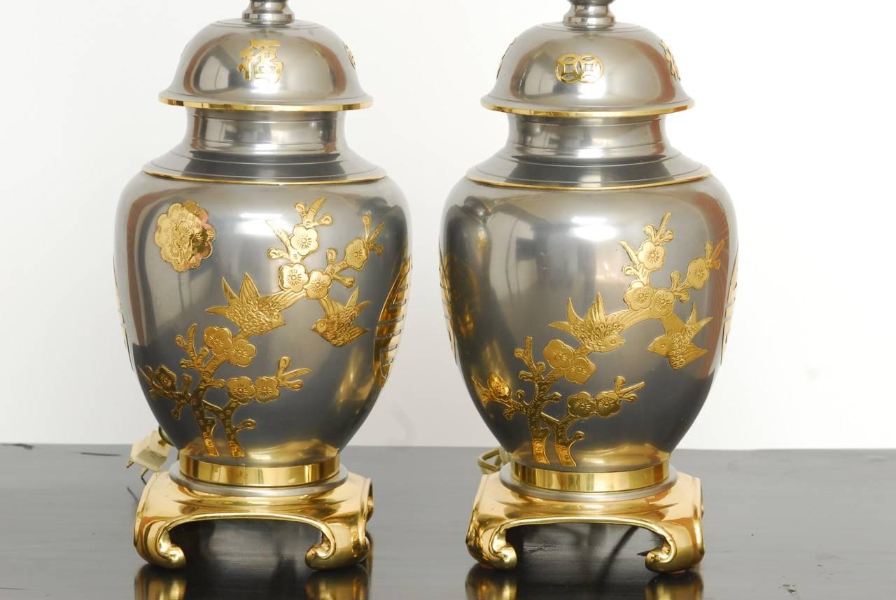 Stunning midcentury pair of Chinese ginger jar vase table lamps constructed from pewter and brass. Features a beautifully polished finish and decorated in the Hollywood Regency taste with Asian flowers, foliage, birds, and prosperity emblems. Each