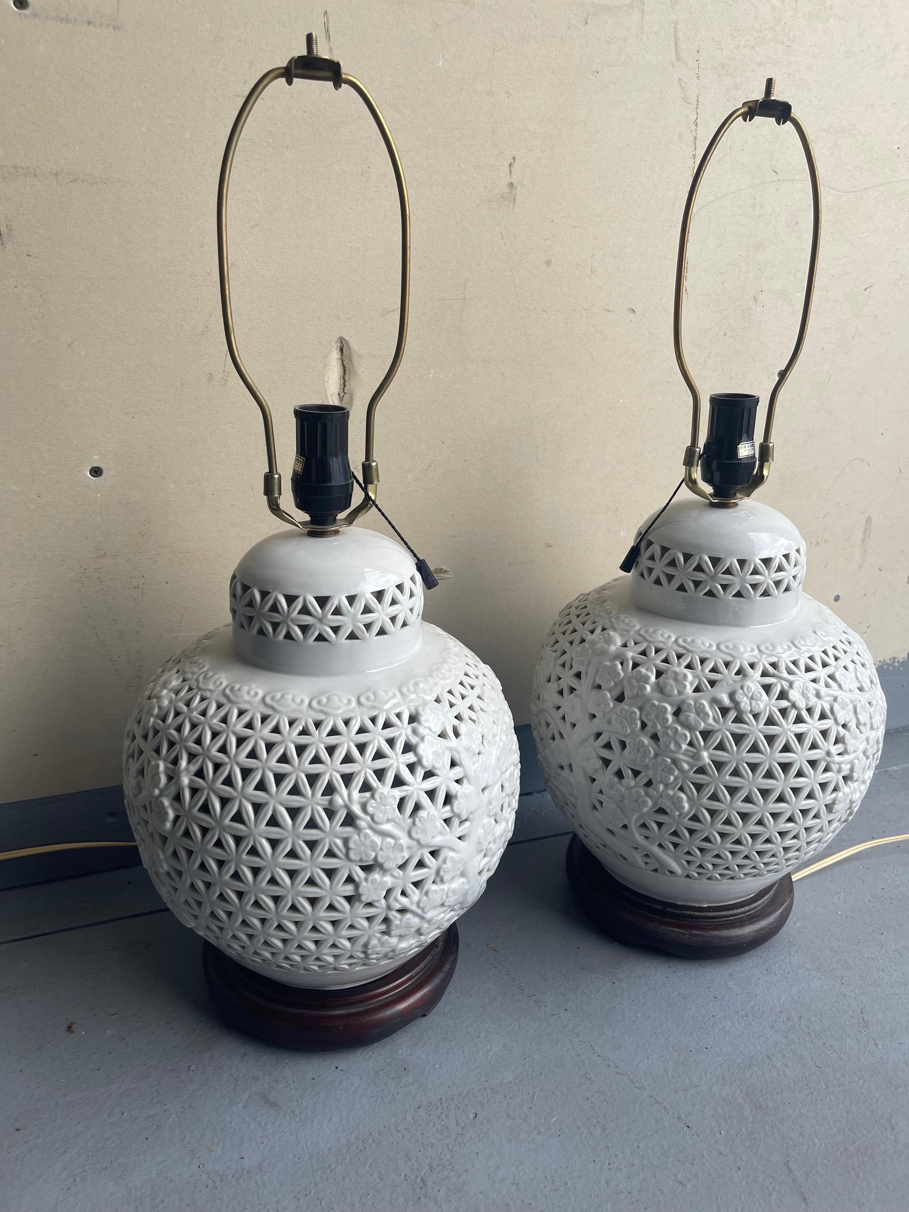 Beautiful and chic pair of Hollywood Regency style Chinese-inspired Blanc de Chine pierced table lamps, circa 1950s, These incredible table lamps are mounted on wooden bases and measure 10