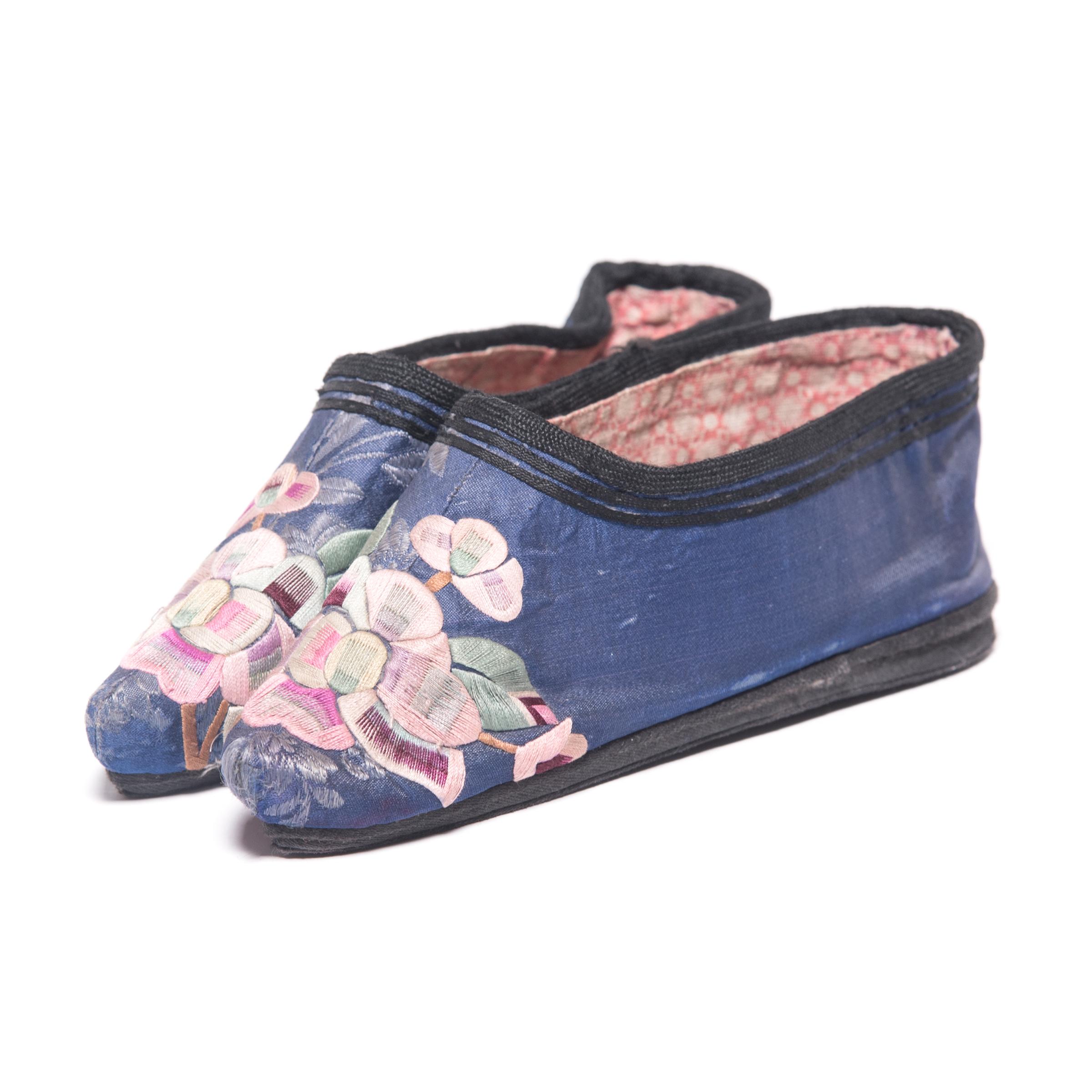 These pointed silk slippers, beautifully embroidered with pink plum blossoms, were shaped to resemble a lotus bud and enhanced the diminutive shape of bound feet. A practice that began in the Tang dynasty and reached the height of its popularity