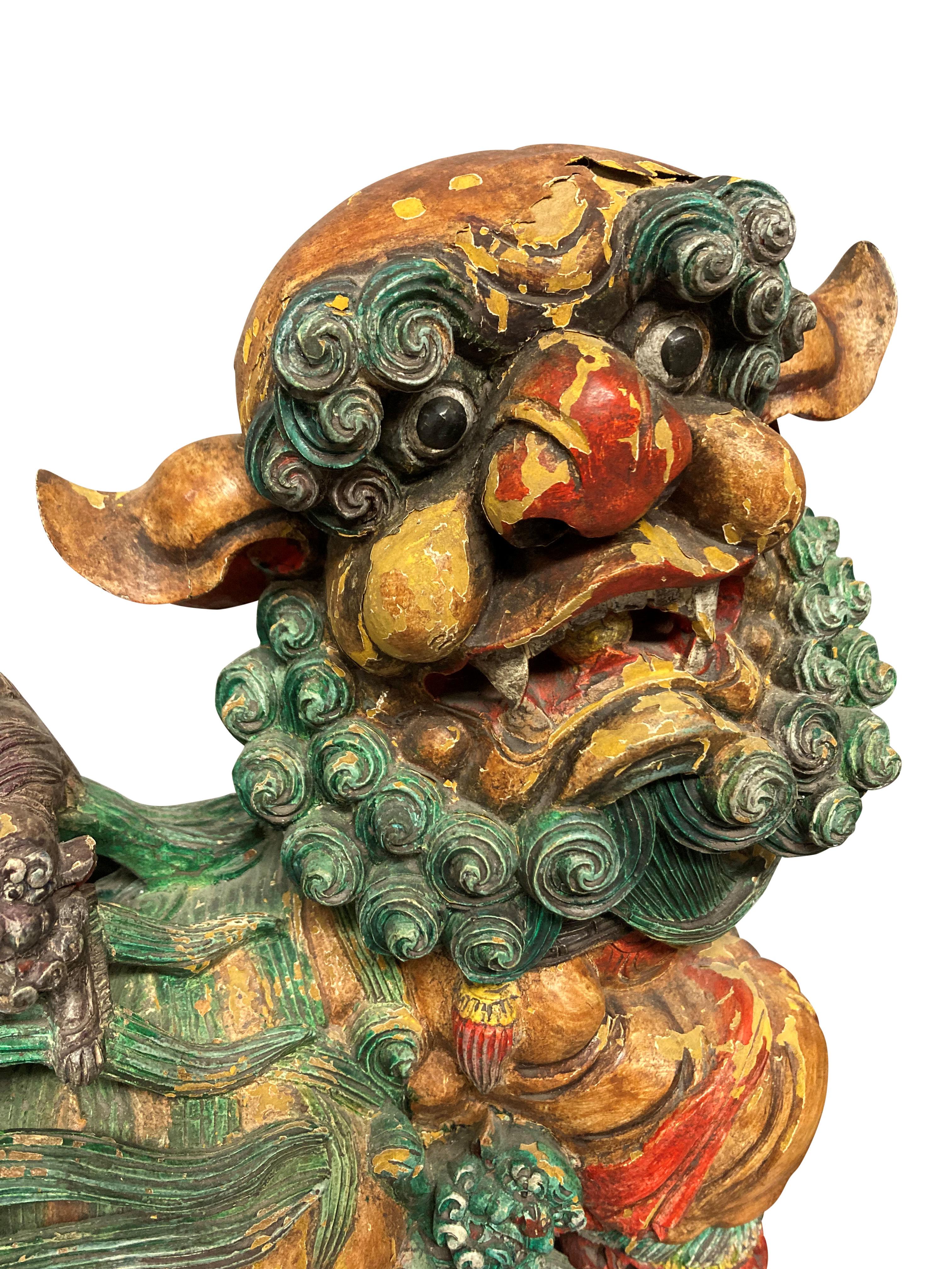 A pair of Chinese carved wood and polychrome painted and gilded foo dogs, in their original paints.