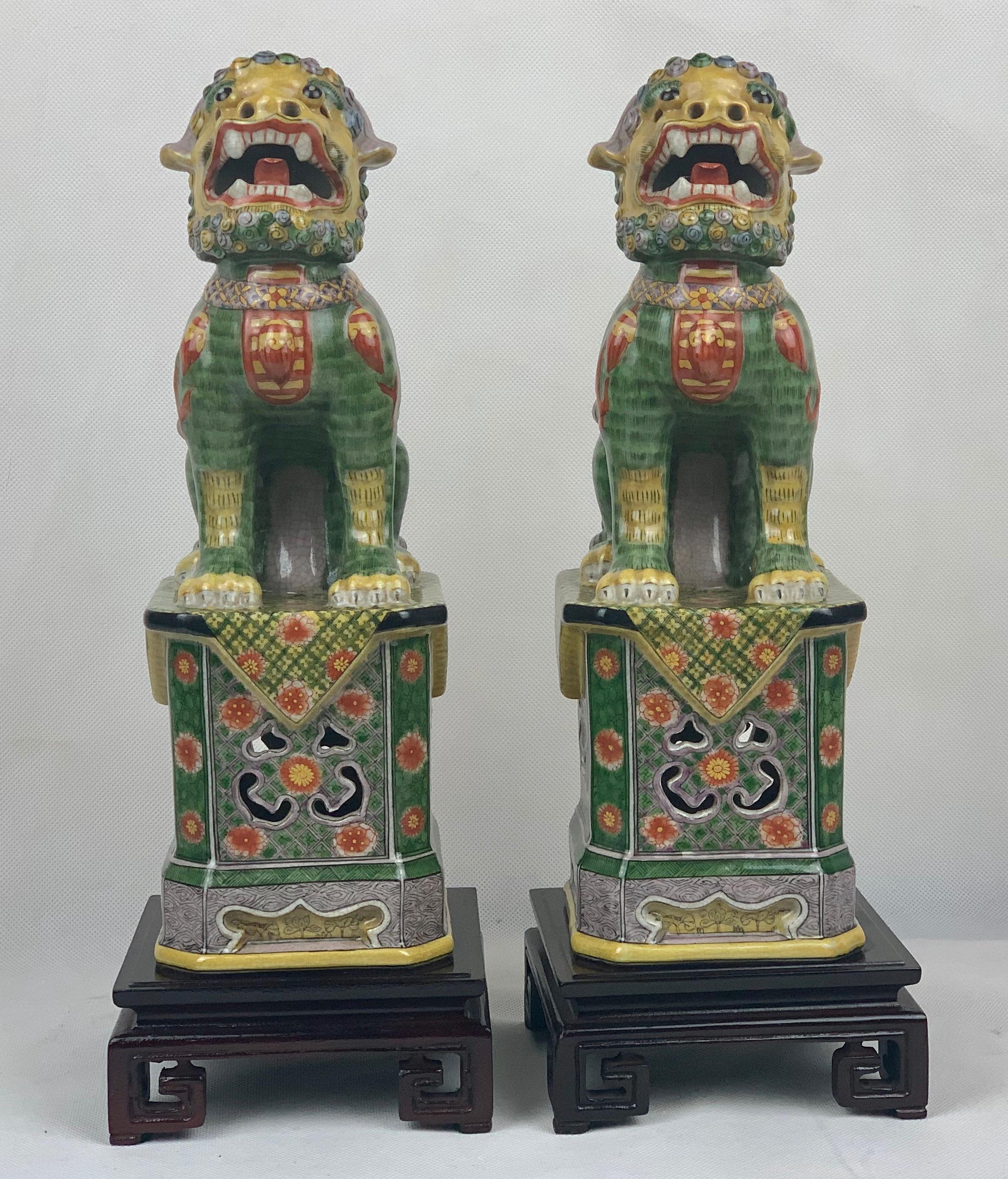 Pair of Chinese polychromed porcelain Foo Dogs or Foo Lions on stands. Their front legs are separated from their bodies as if they are about to roar at approaching visitors. They are finely modeled and hand decorated in shades of Ming Green,