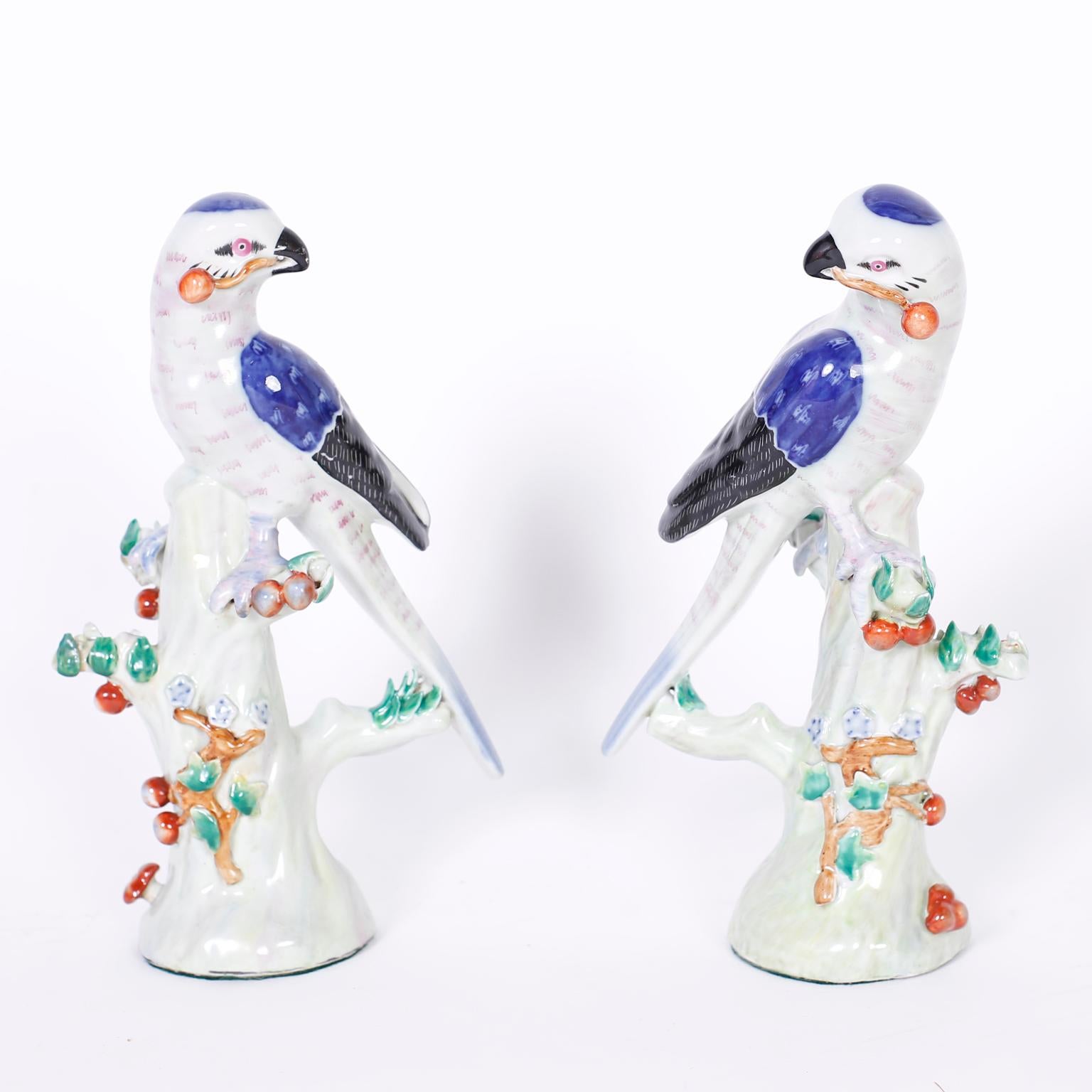 Lofty pair of Chinese porcelain birds delicately hand painted with blues and black, perched on stylized fruit baring trees.